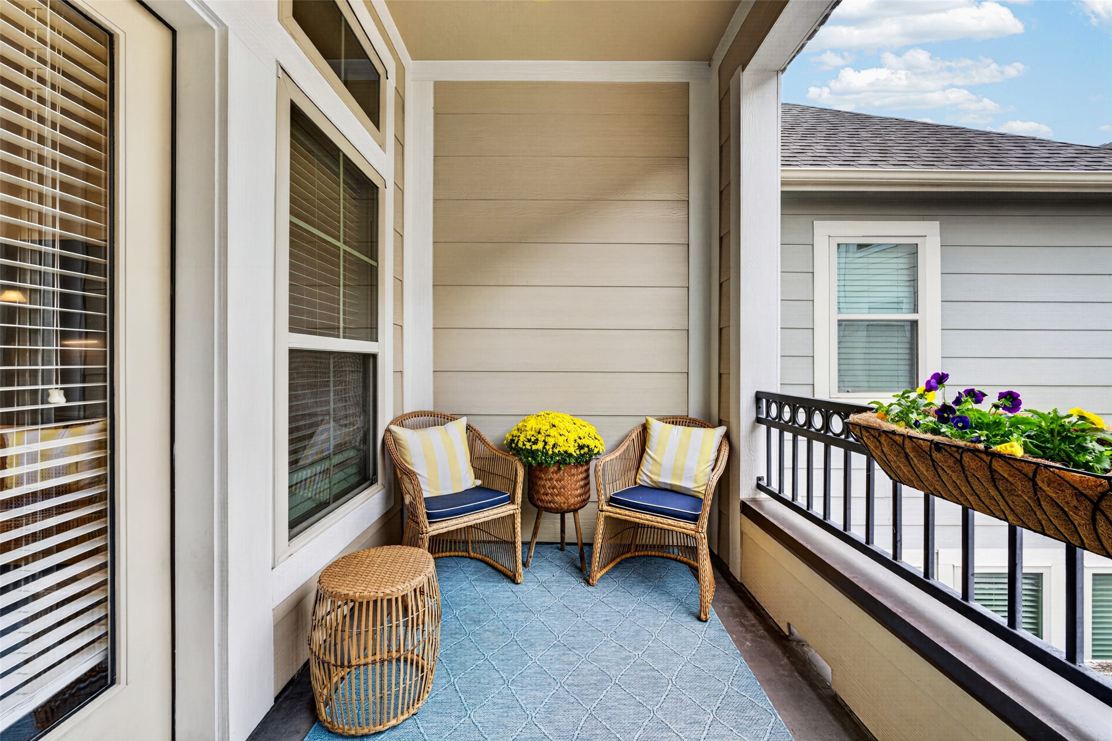 Covered balcony on the second floor offers a cozy outdoor retreat with seating