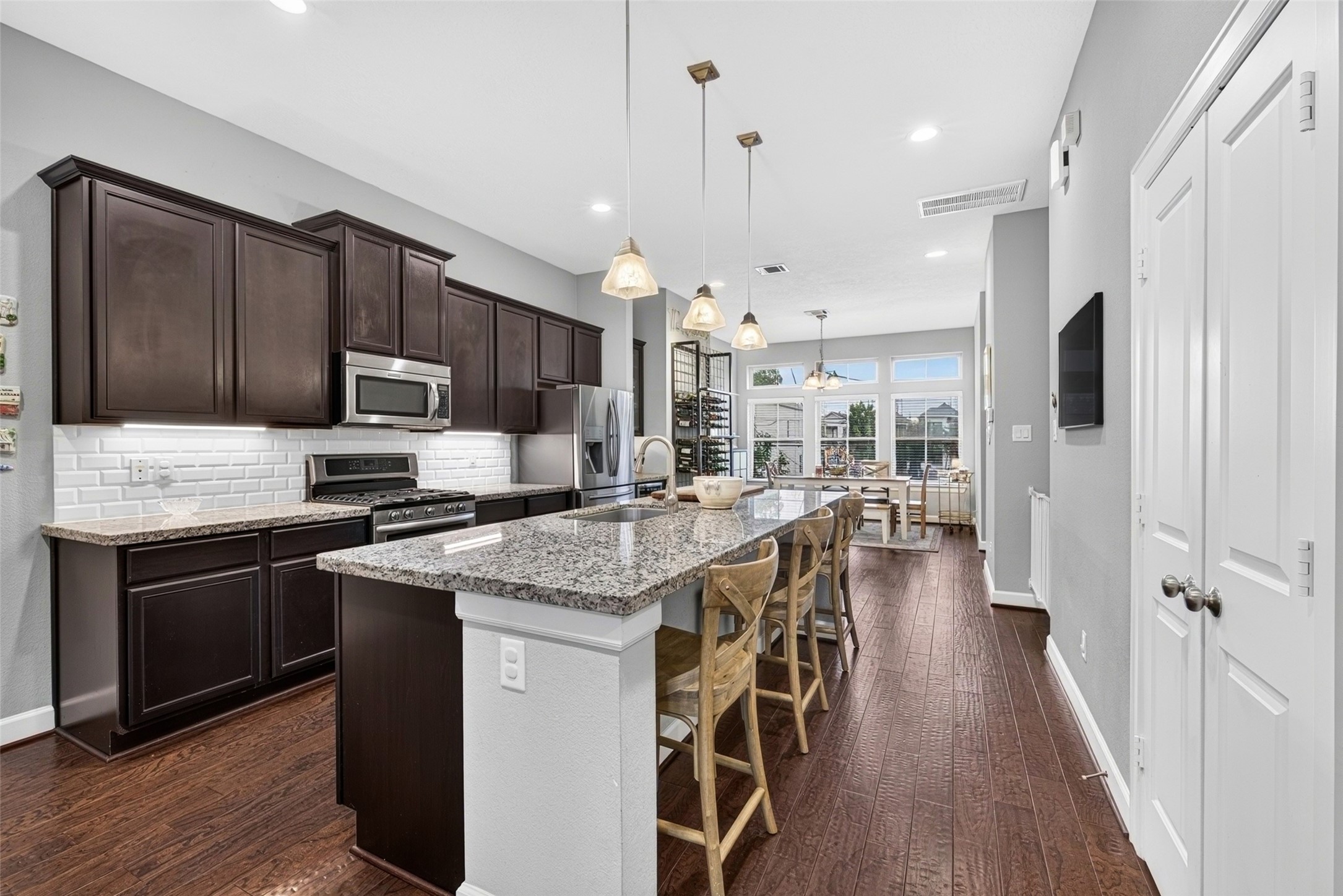 Open kitchen with granite countertops, rich wood cabinetry, stainless steel appliances, and breakfast bar seating.