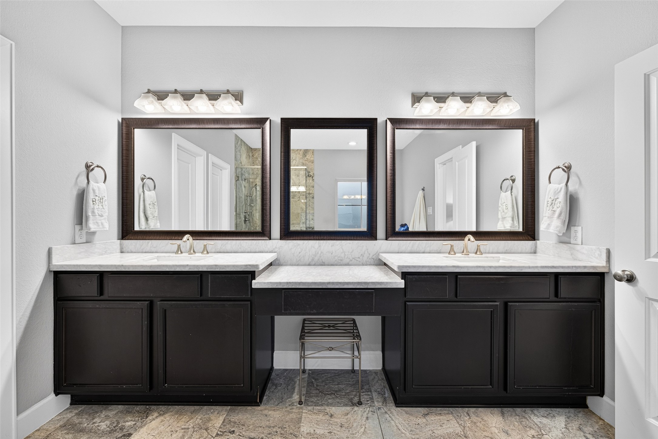 Spacious primary bath featuring a soaking tub, separate glass-enclosed shower, and dual vanities.