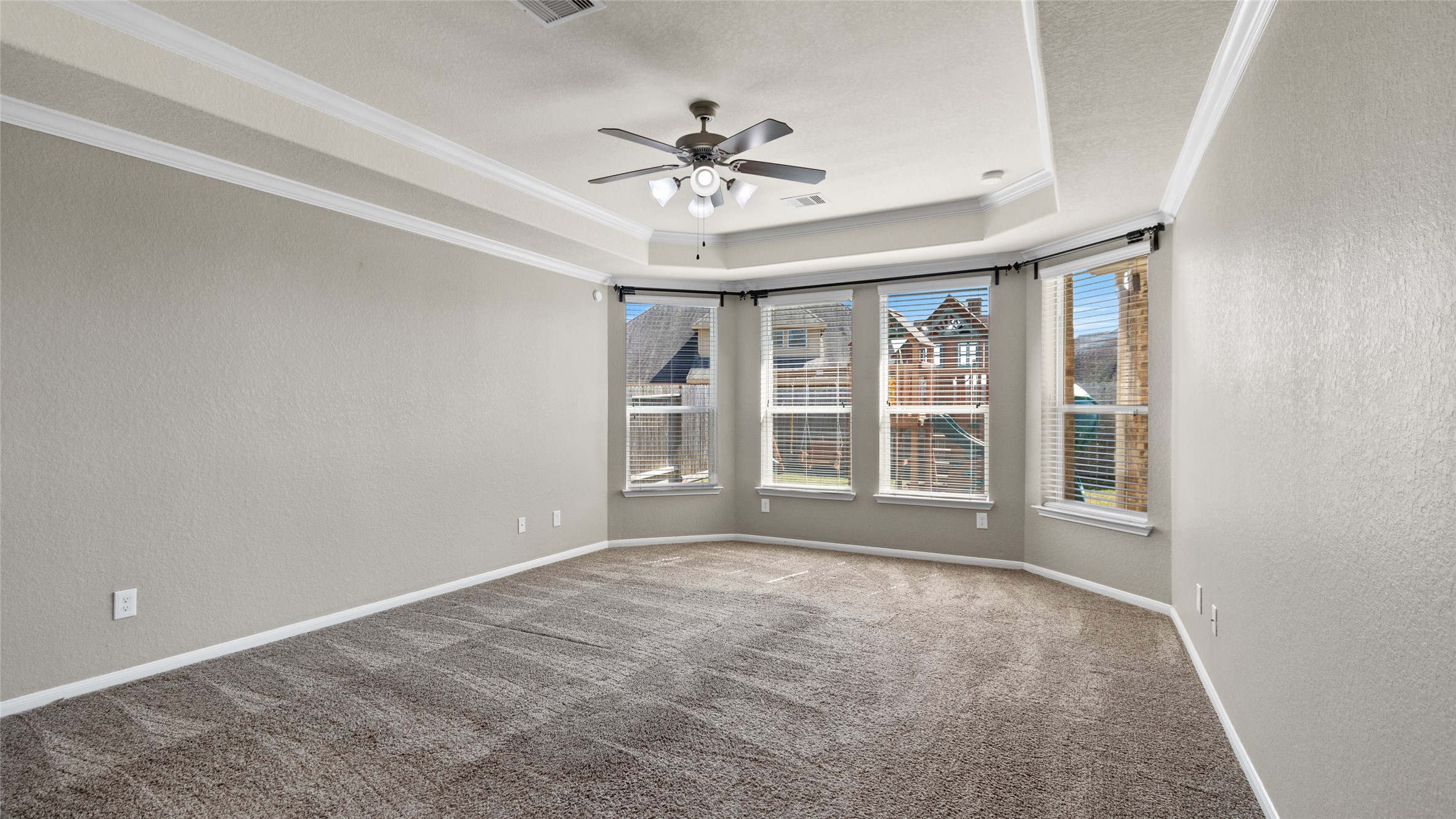 This is the primary suite located on the first level of the home with a sitting area around the windows, with tray ceiling and cove ligthing giving this room a very stately feel.
