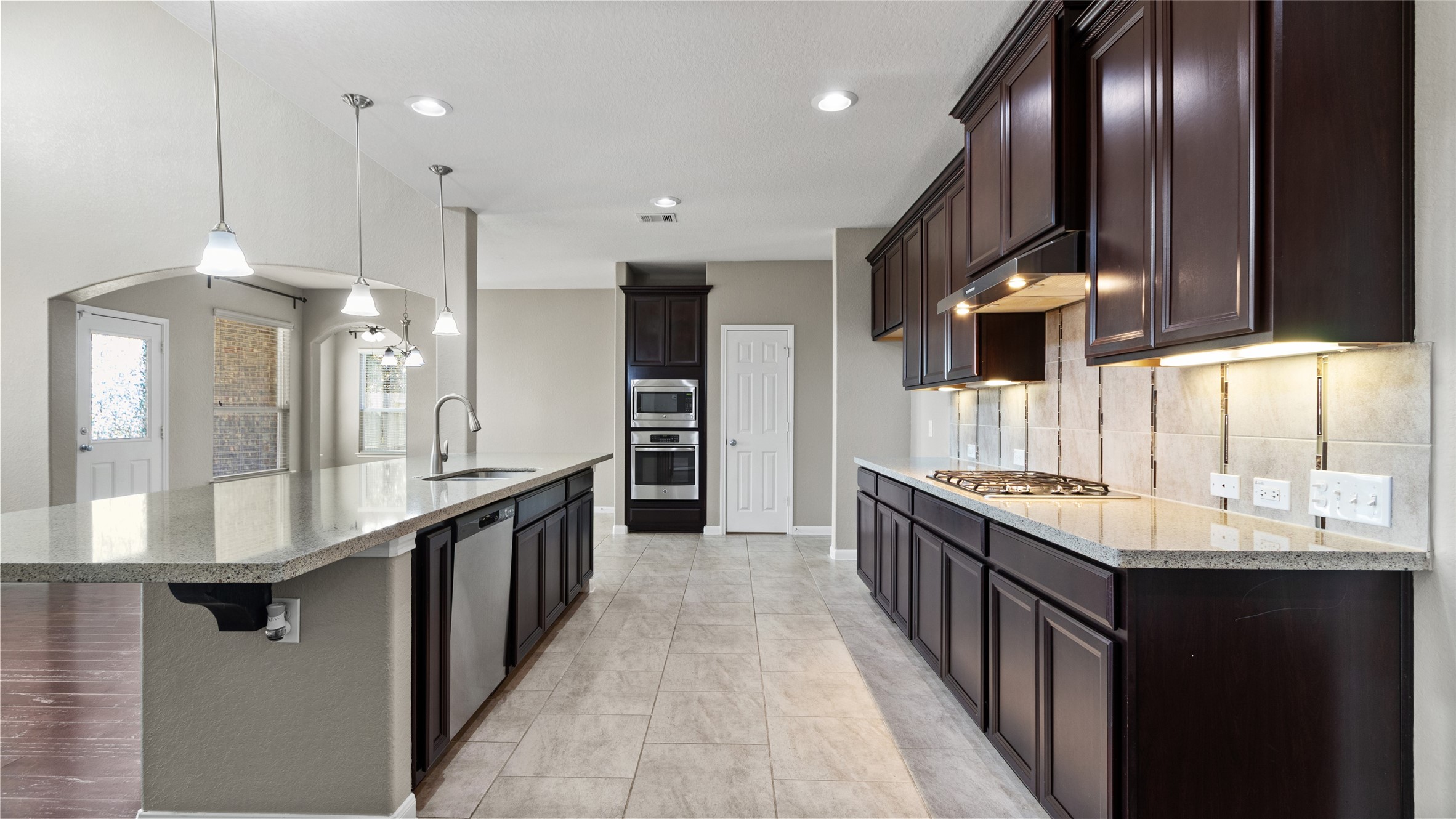 This spacious and inviting kitchen features abundant storage, under-cabinet lighting, a gas cooktop, and a massive island equipped with two deep stainless steel sinks. Open to both the living and breakfast areas, this kitchen is the perfect space for daily gathering and entertaining.