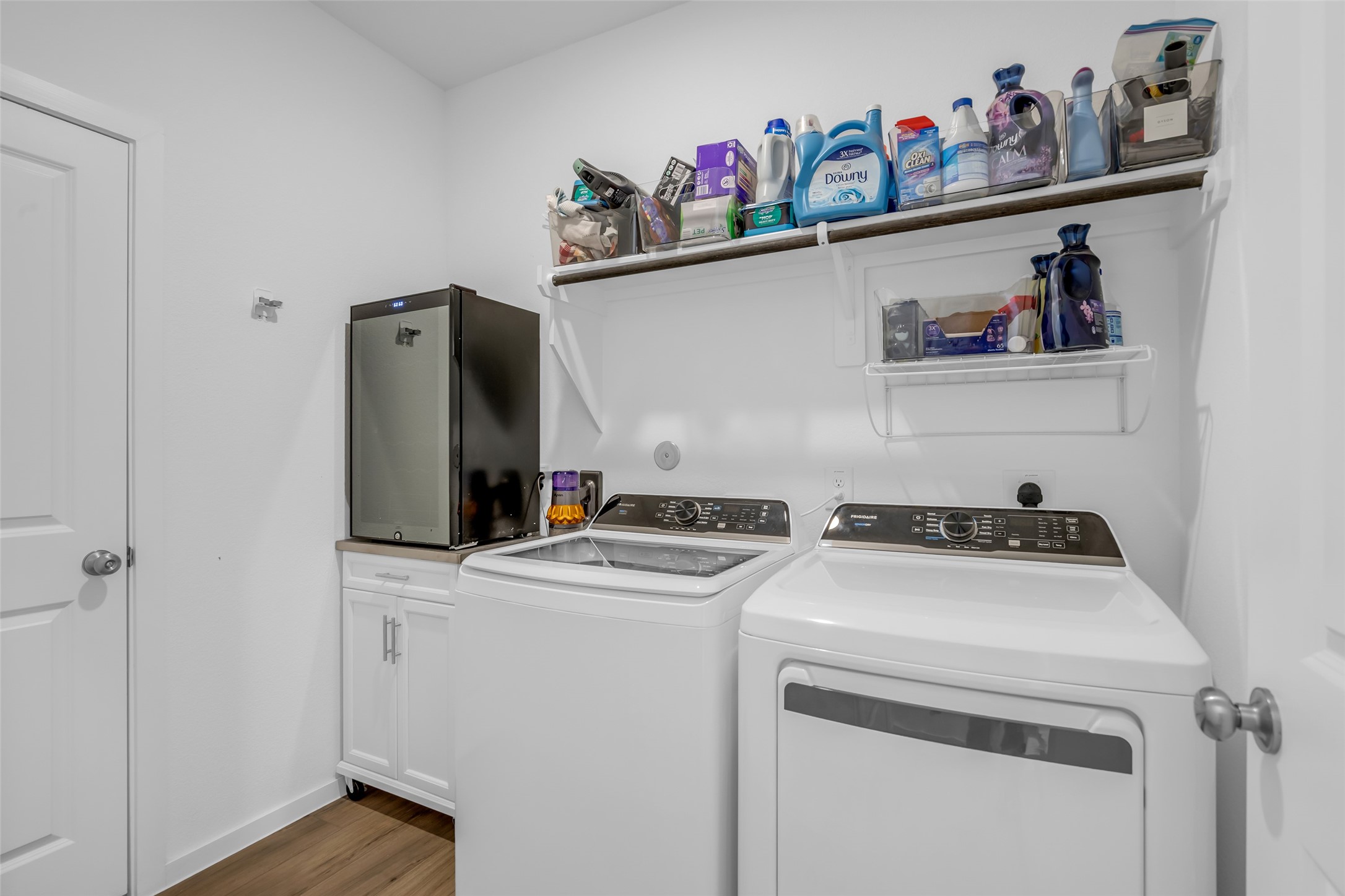Efficient laundry room featuring modern washer and dryer, ample shelving for storage, and a convenient utility cabinet.