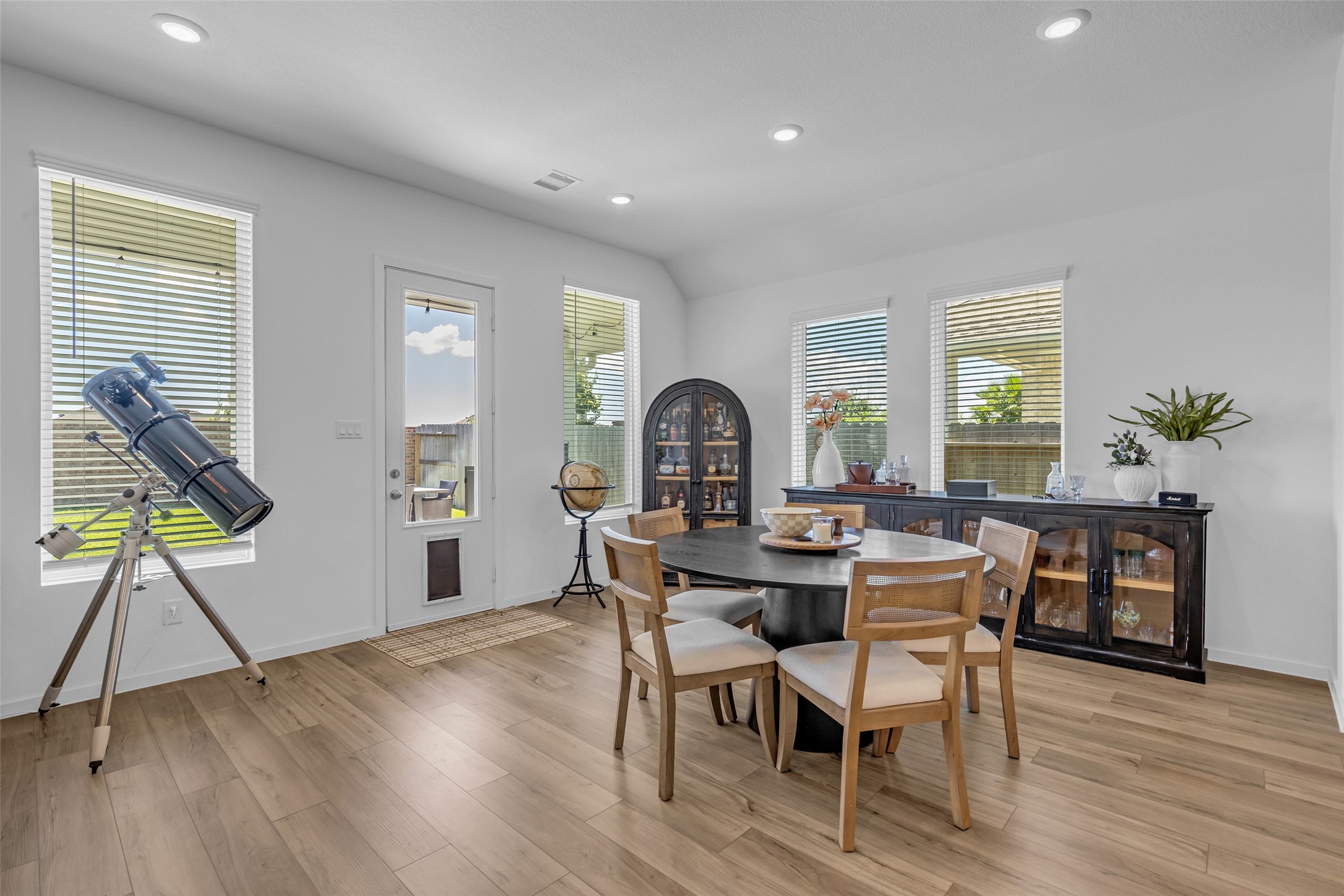 Bright and inviting dining area with large windows, sleek wood flooring, and modern furnishings, perfect for family gatherings.