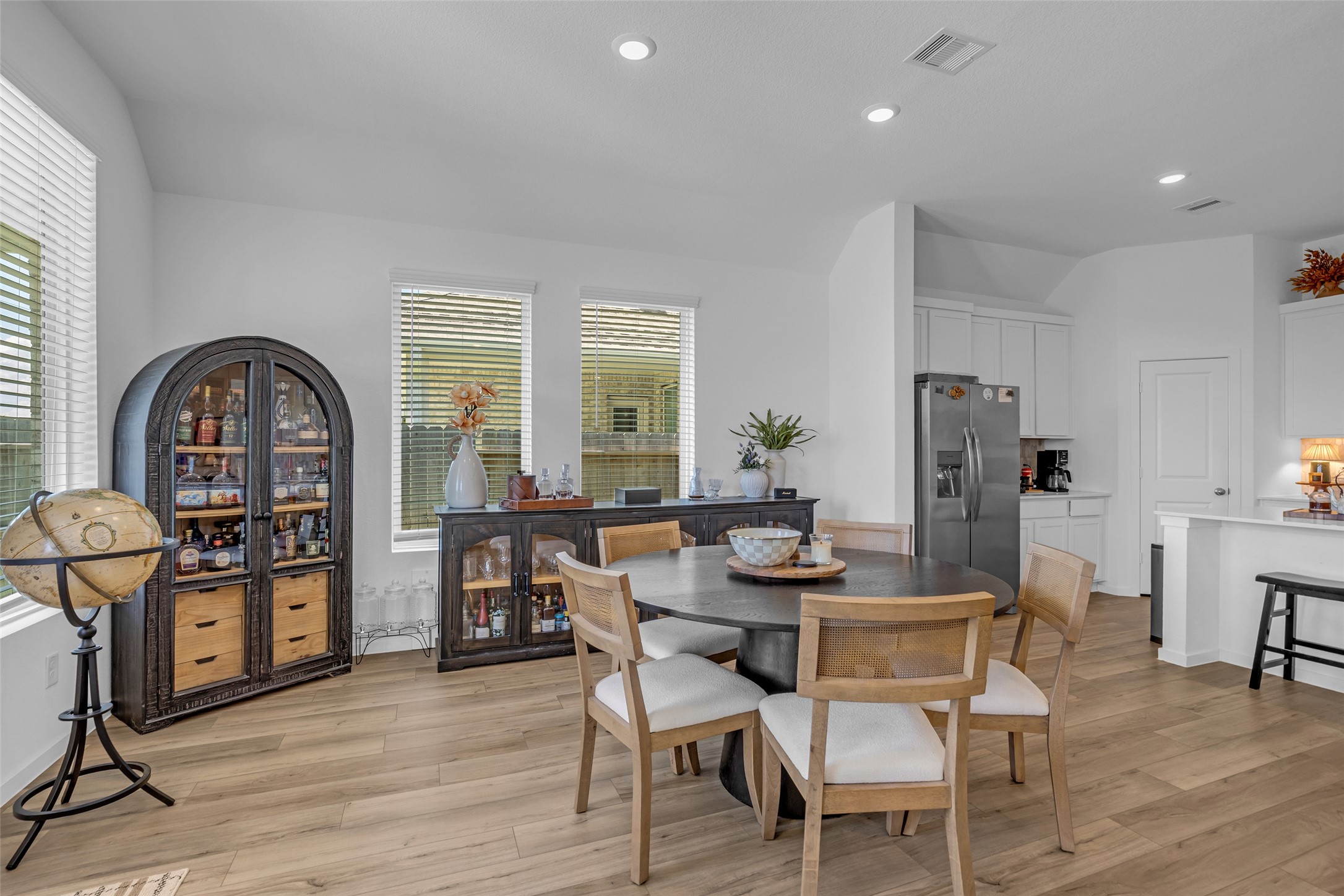 Bright and inviting dining area with modern woodlike flooring, a stylish round table, and ample natural light from large windows. Bright and inviting dining area with modern woodlike flooring, a stylish round table, and ample natural light from large windows.