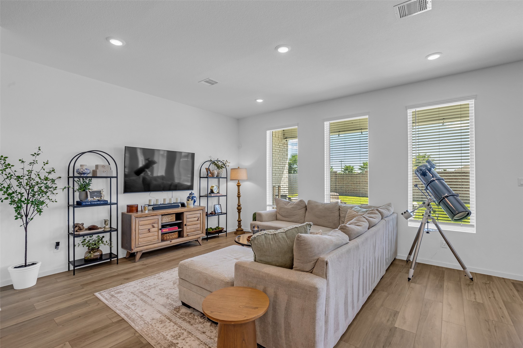 Bright and inviting living room with large windows, comfortable sectional sofa, and elegant wood flooring, perfect for relaxation and entertaining.