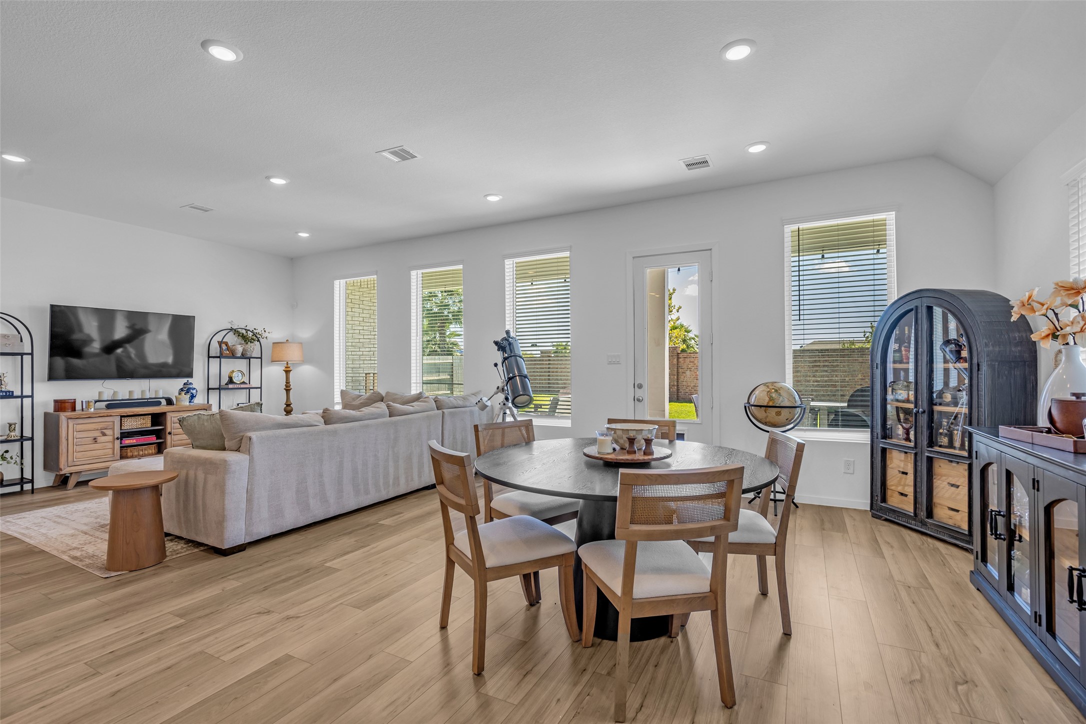 Spacious and bright open-concept living and dining area featuring sleek hardwood floors, abundant natural light from large windows, and elegant modern furnishings.
