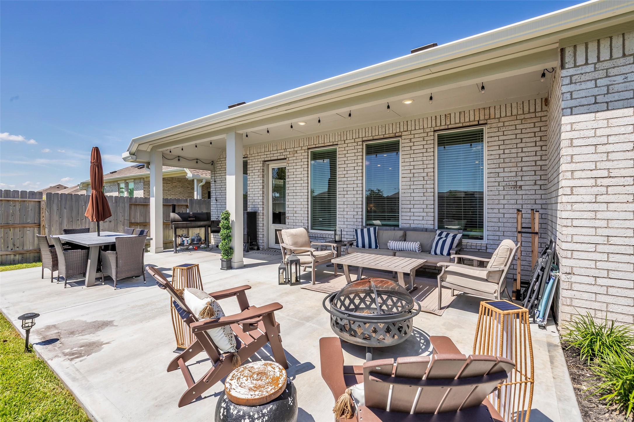 Extended outdoor patio features a spacious seating area, cozy fire pit, and dining set, perfect for entertaining or relaxing in a private fenced yard. Extended outdoor patio features a spacious seating area, cozy fire pit, and dining set, perfect for entertaining or relaxing in a private fenced yard.