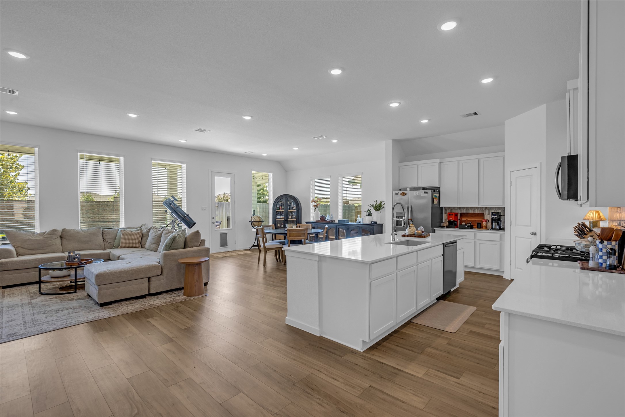 Spacious open-concept living area with abundant natural light, featuring a modern kitchen with a large island, sleek cabinetry, and stainless steel appliances, seamlessly flowing into a cozy living and dining space.