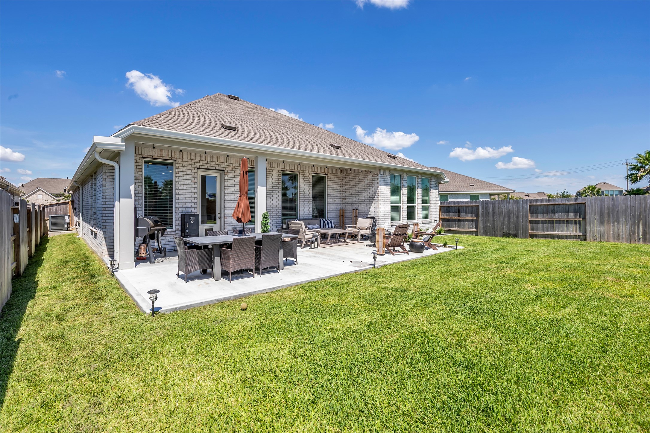 Spacious backyard with a large patio perfect for outdoor dining and relaxation, surrounded by a well-maintained lawn and privacy fence.