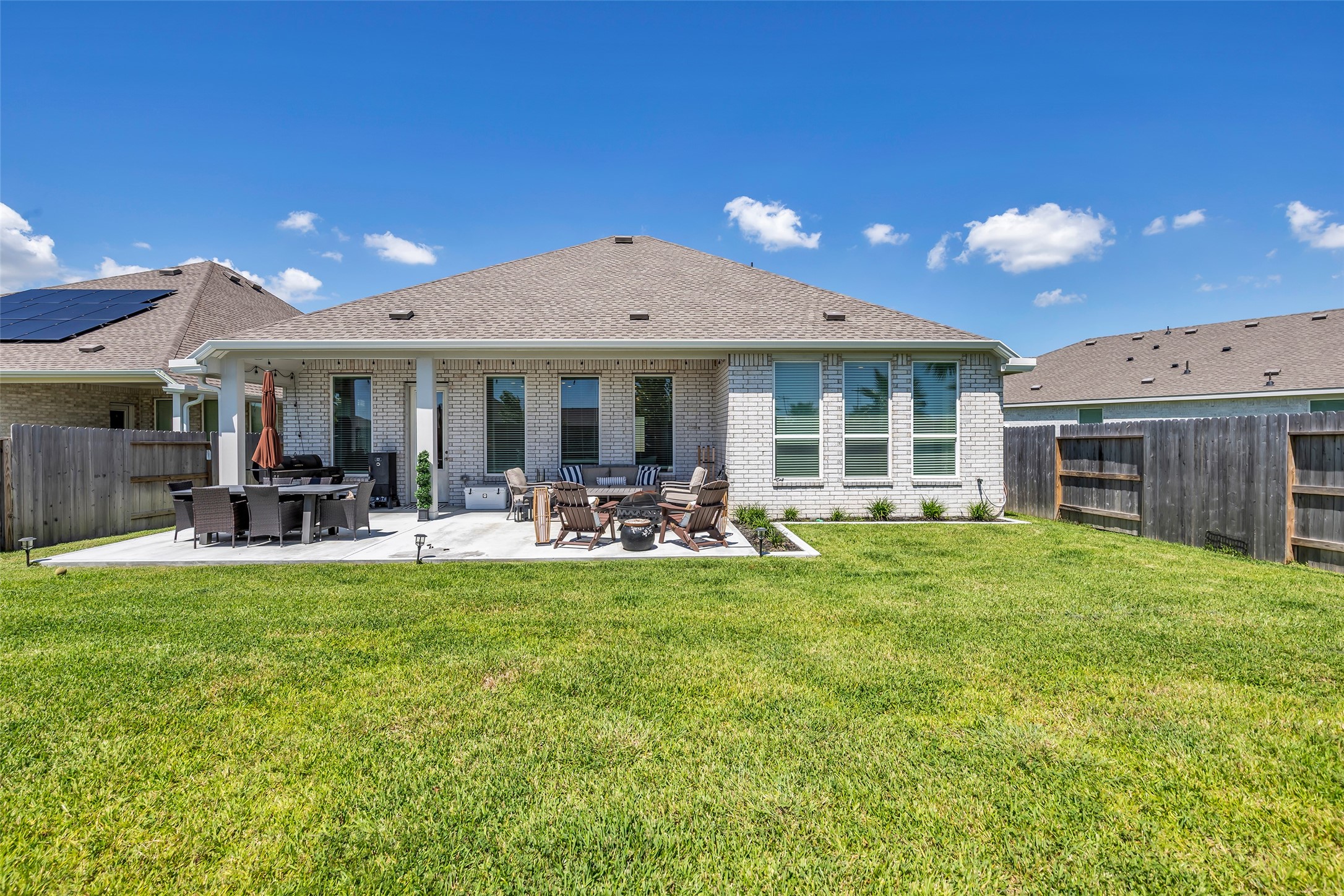 Spacious backyard with a well-maintained lawn, featuring a modern patio area perfect for outdoor dining and entertaining.