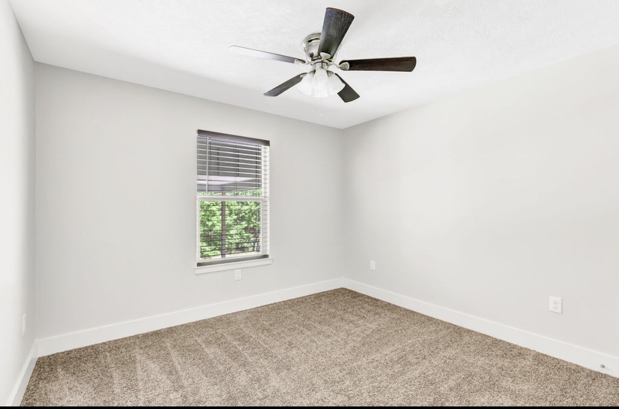 Bright and inviting bedroom with fresh neutral tones, cozy carpeting, and a ceiling fan for ultimate comfort.