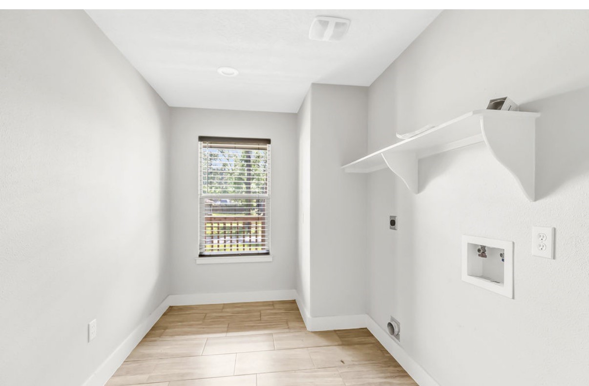 Bright utility room with sleek wood-look flooring, built-in shelf, and a window for natural light.