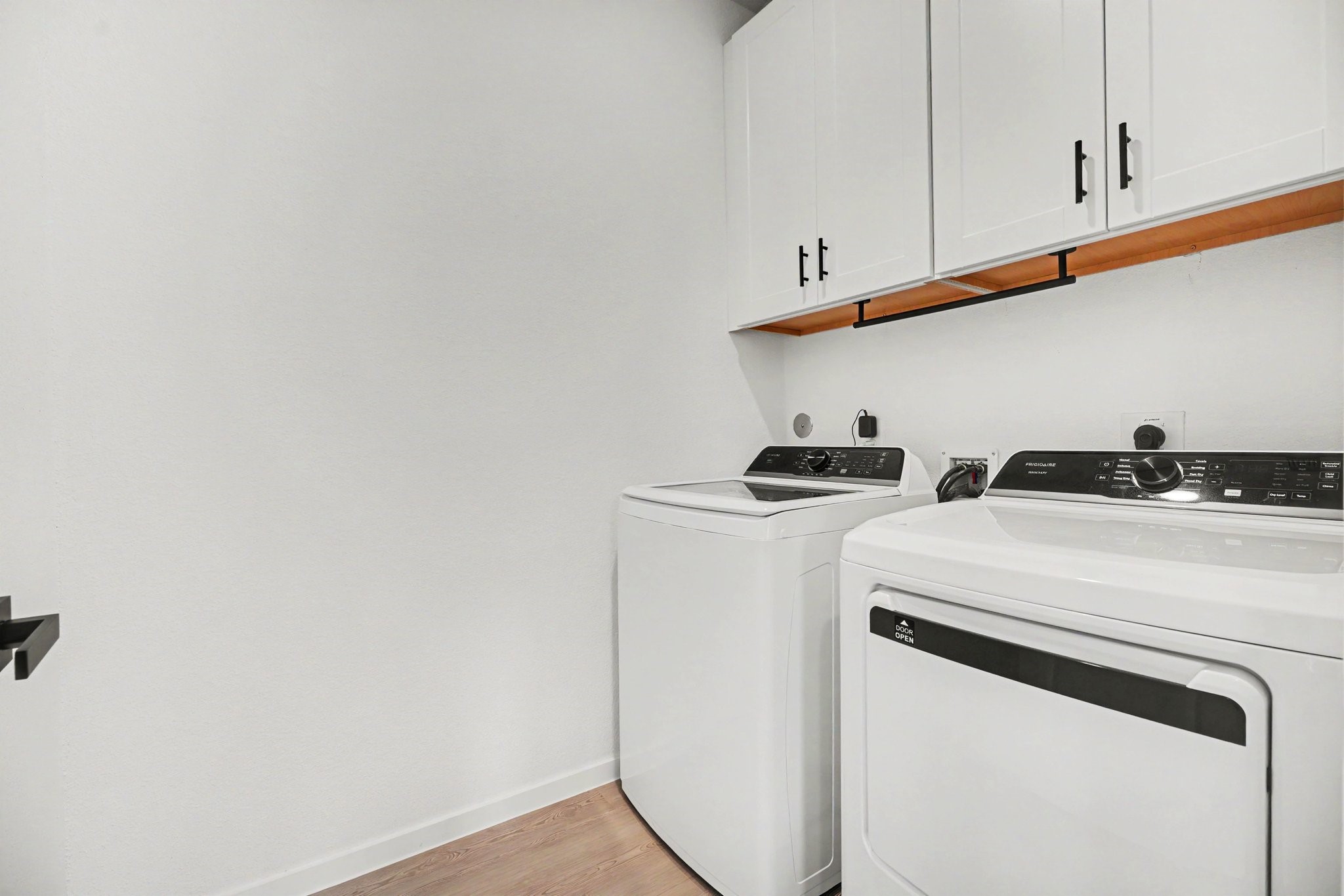 Laundry room with upper cabinetry providing additional storage for supplies and household essentials.