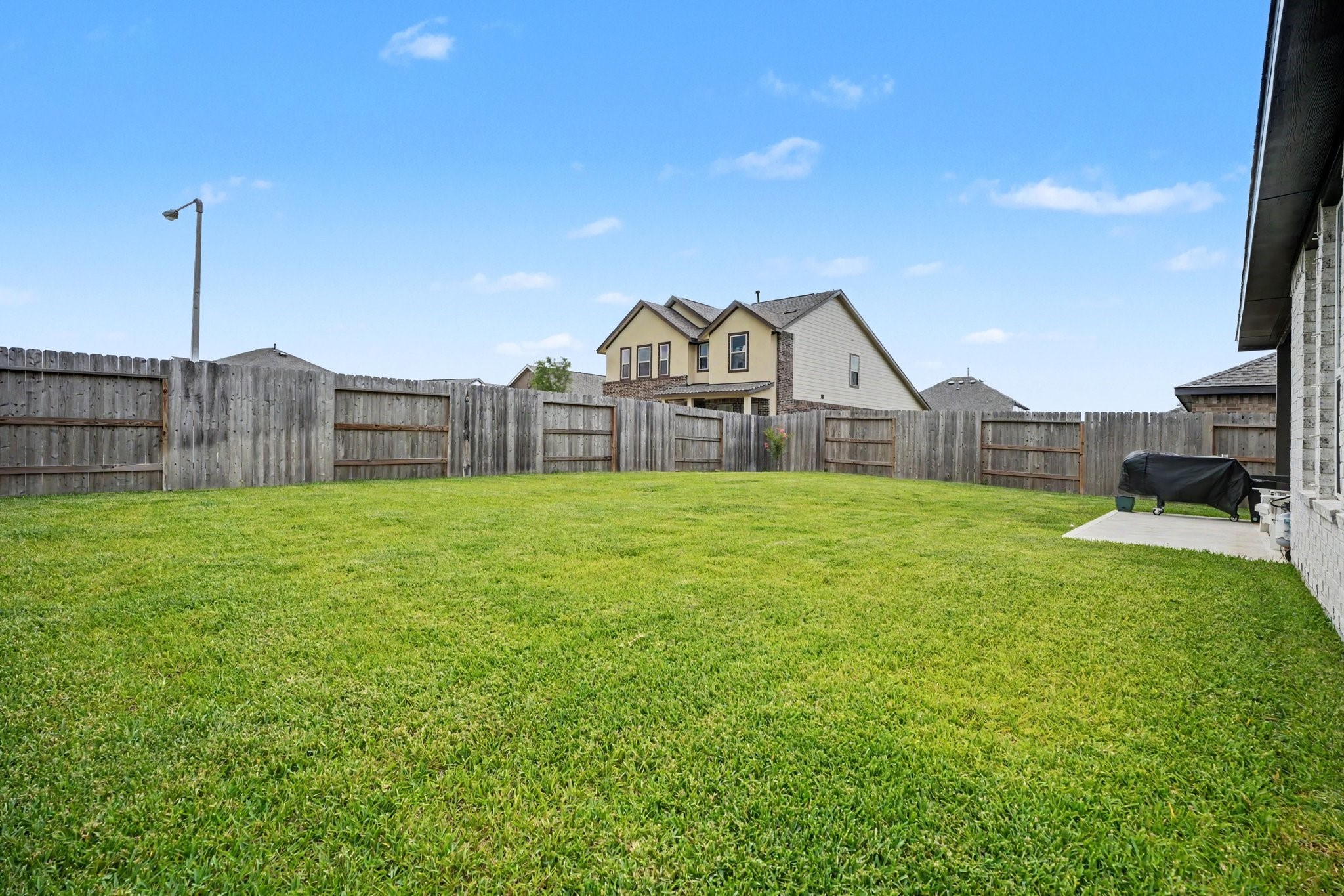 Alternate view of the backyard showcasing the spacious lawn and fully fenced yard.
