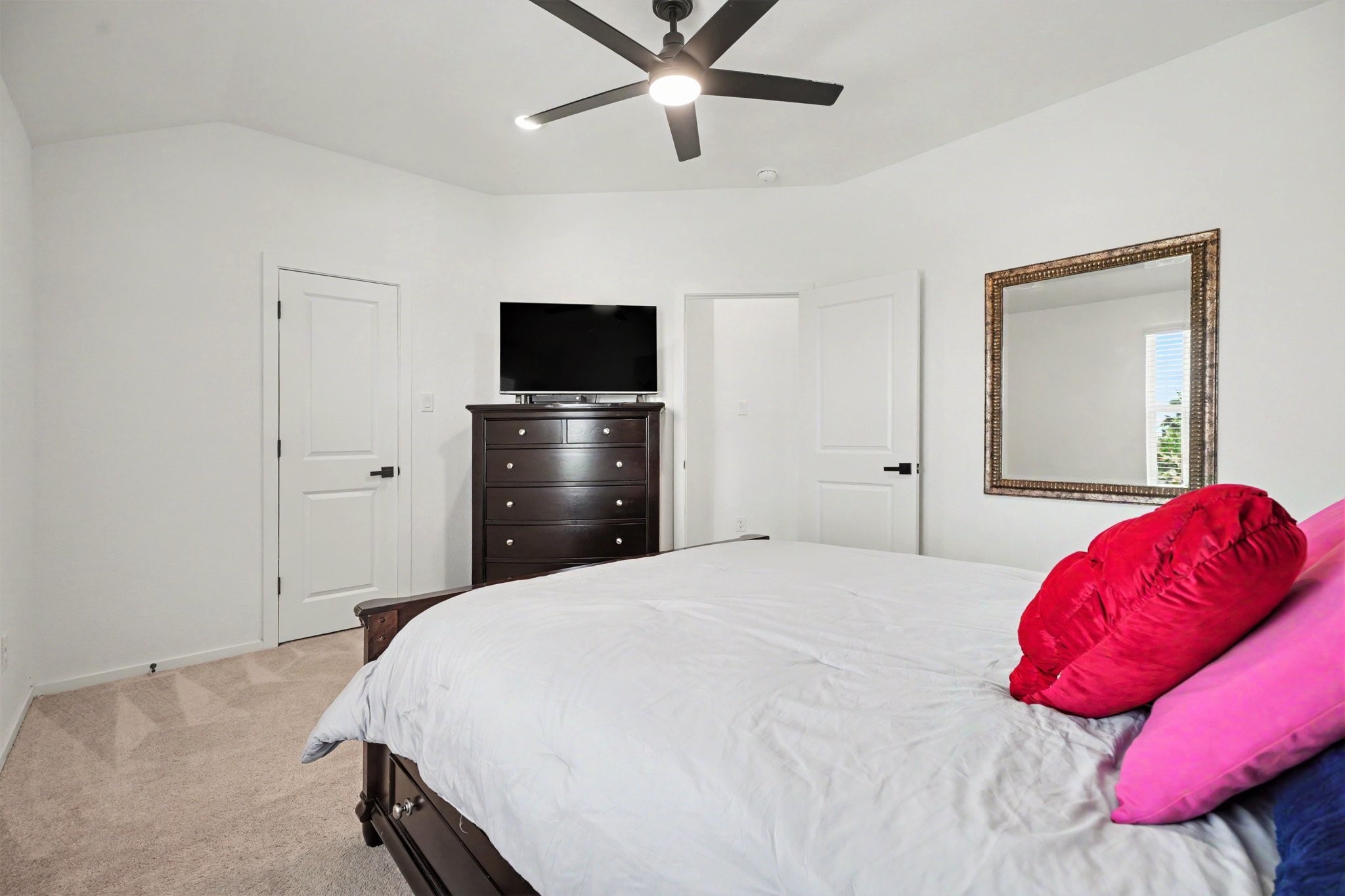 Secondary bedroom with vaulted ceilings, plush carpeting, and ample space for a variety of furniture arrangements.