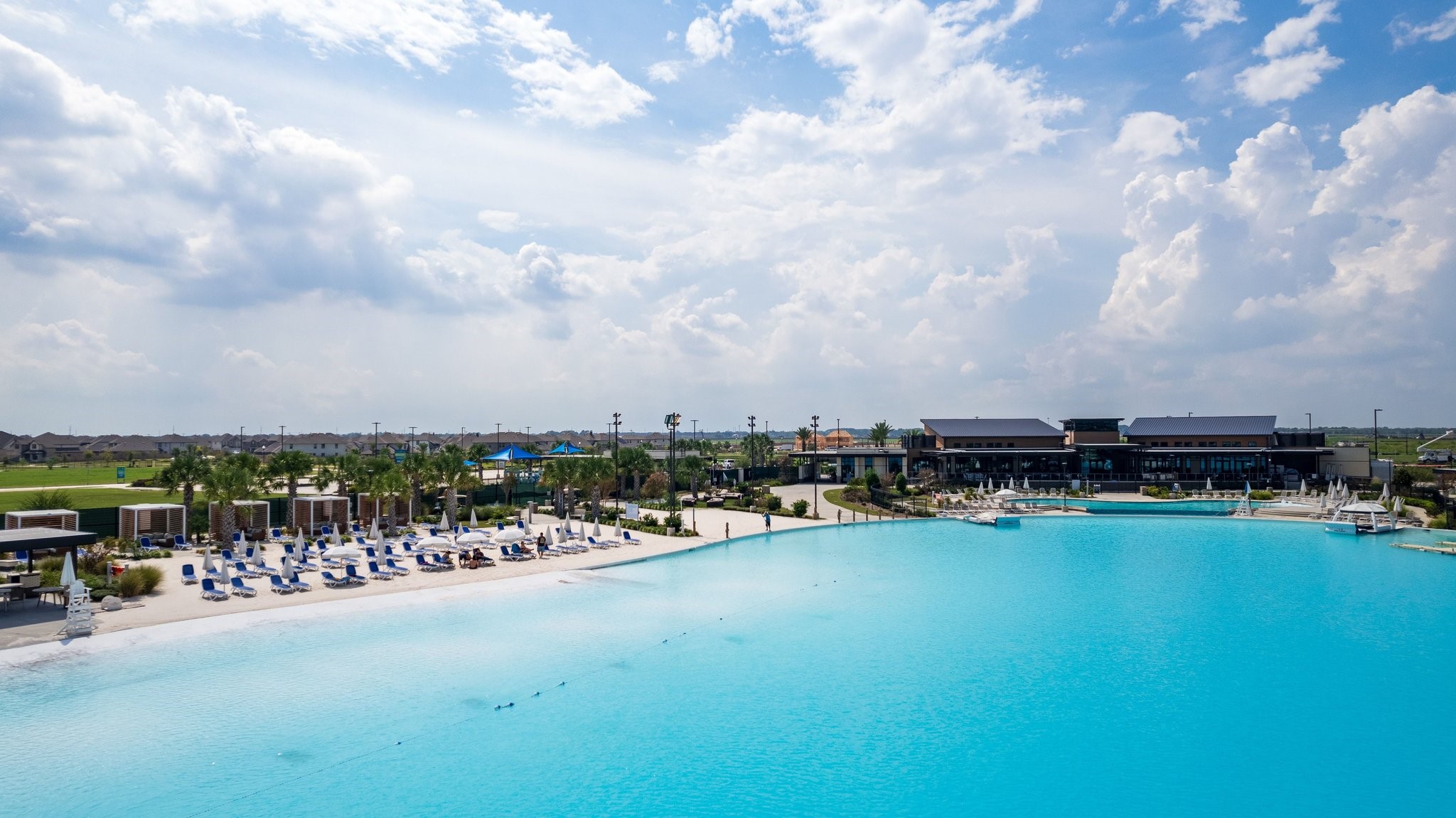 A crystal-clear lagoon creates a resort-inspired setting with sandy beaches, lounge areas, and waterfront recreation.