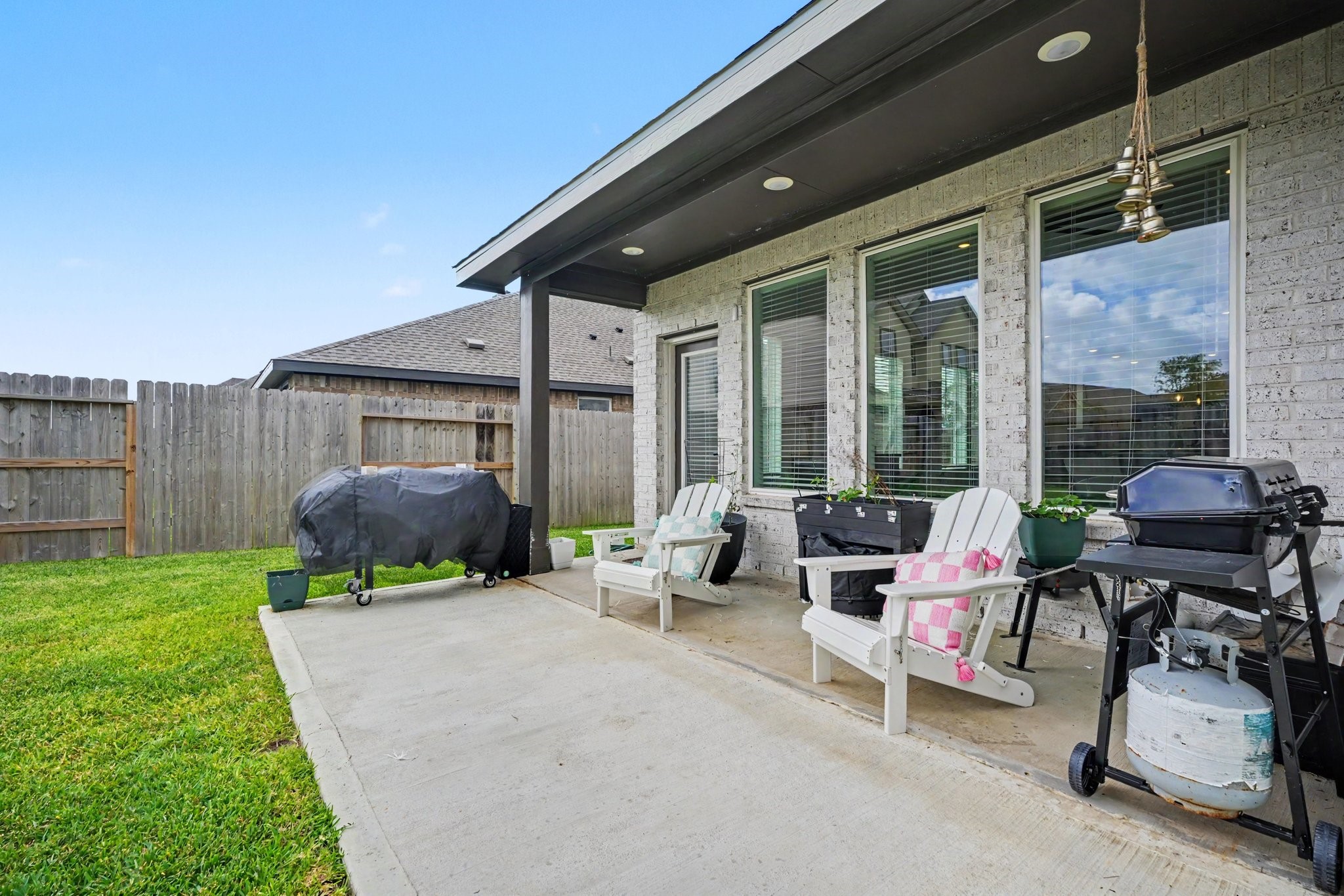 Covered patio with space for outdoor seating and grilling, creating a comfortable spot to enjoy the backyard.