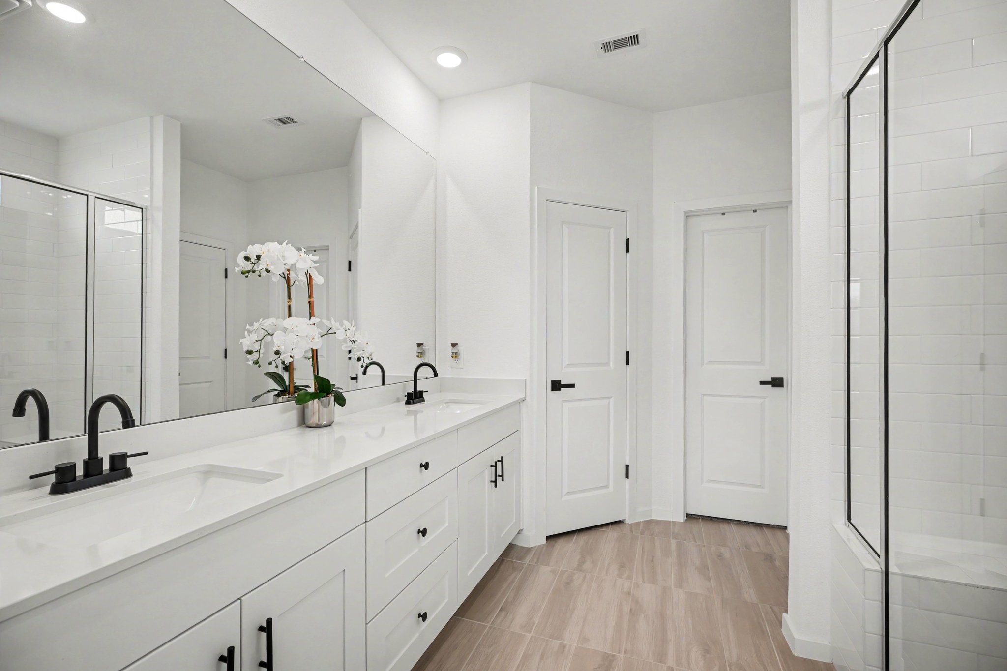 Well-appointed primary bath featuring a dual-sink vanity, expansive mirror, abundant cabinet and drawer storage, and a dedicated linen closet.