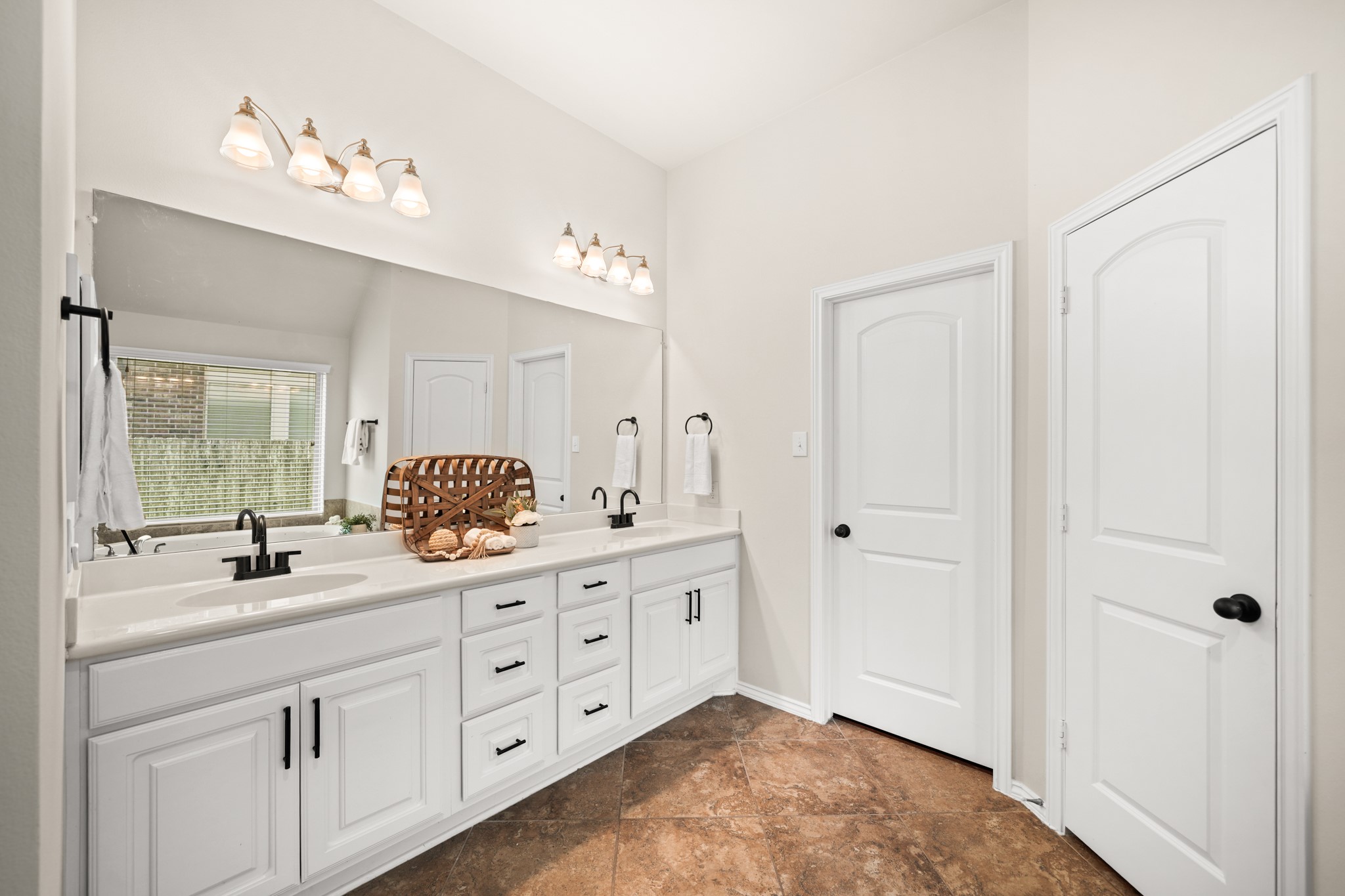 Primary bathroom with dual sinks, soaking tub, separate shower, and large walk-in closet