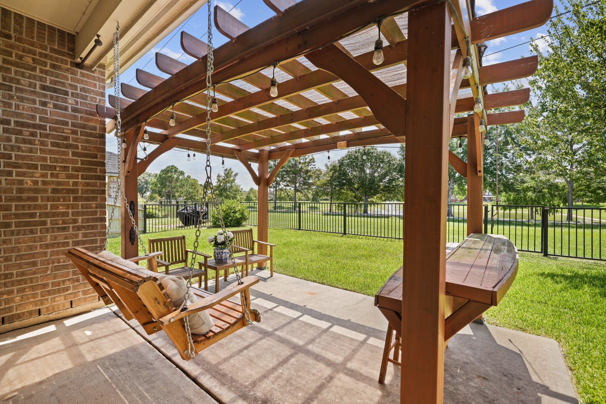 Enjoy outdoor living beneath the custom pergola complete with swing seating, bar area, and space for entertaining. Enjoy outdoor living beneath the custom pergola complete with swing seating, bar area, and space for entertaining.