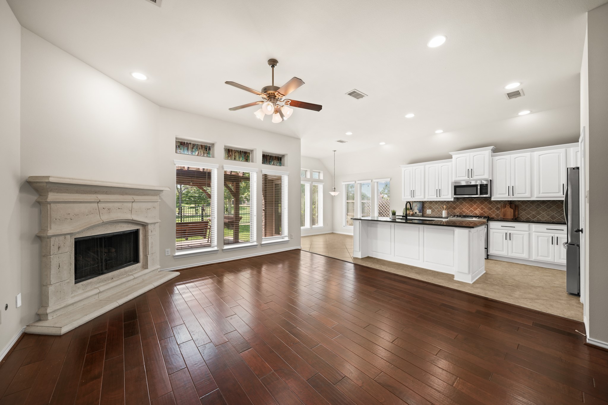 Spacious family room with hardwood flooring, elegant stone fireplace, and an open-concept layout. Spacious family room with hardwood flooring, elegant stone fireplace, and an open-concept layout.