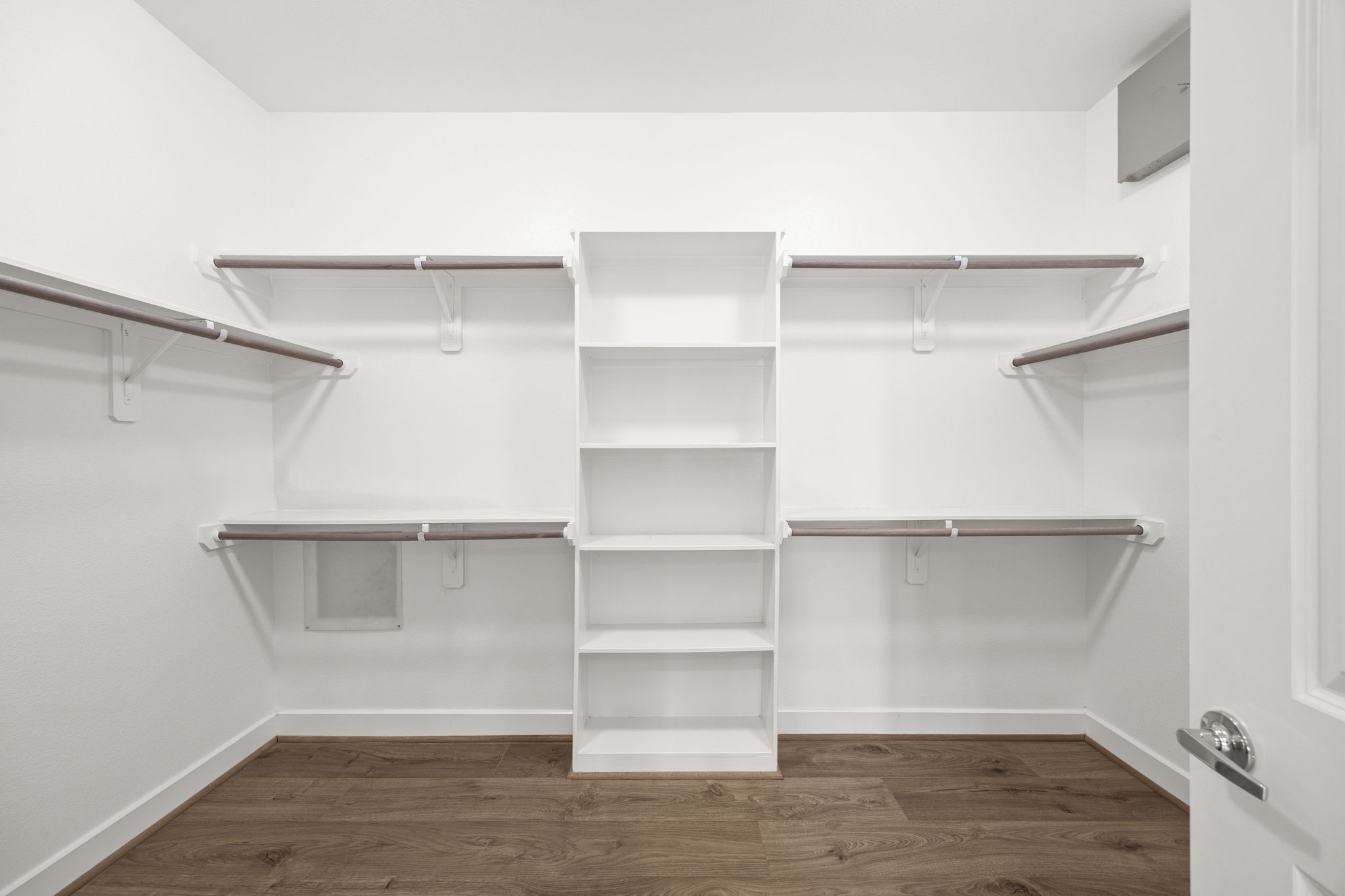 The primary walk-in closet has plenty of space for hanging, as well as built-in shelves. Enough space to add a central prep island in the future!