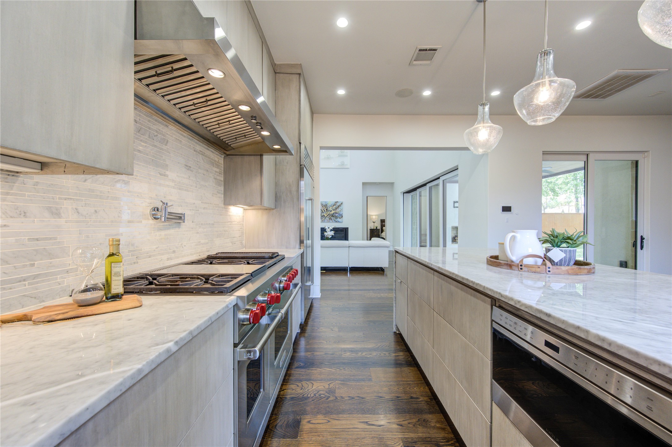 The modern kitchen boasts sleek stainless steel appliances, a spacious marble-topped island, elegant pendant lighting, and a stylish tile backsplash, offering a perfect blend of functionality and contemporary design.