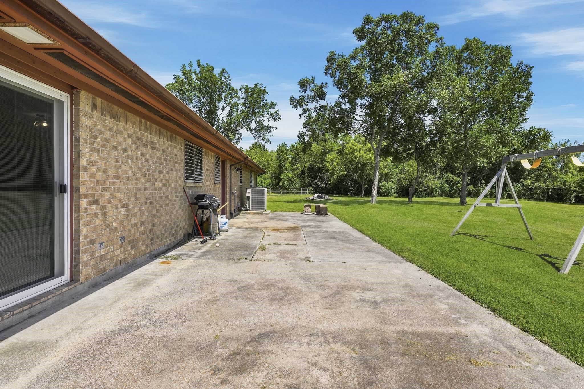 Spacious backyard with a patio area, perfect for outdoor entertaining, complemented by lush green lawn and mature trees for added privacy.