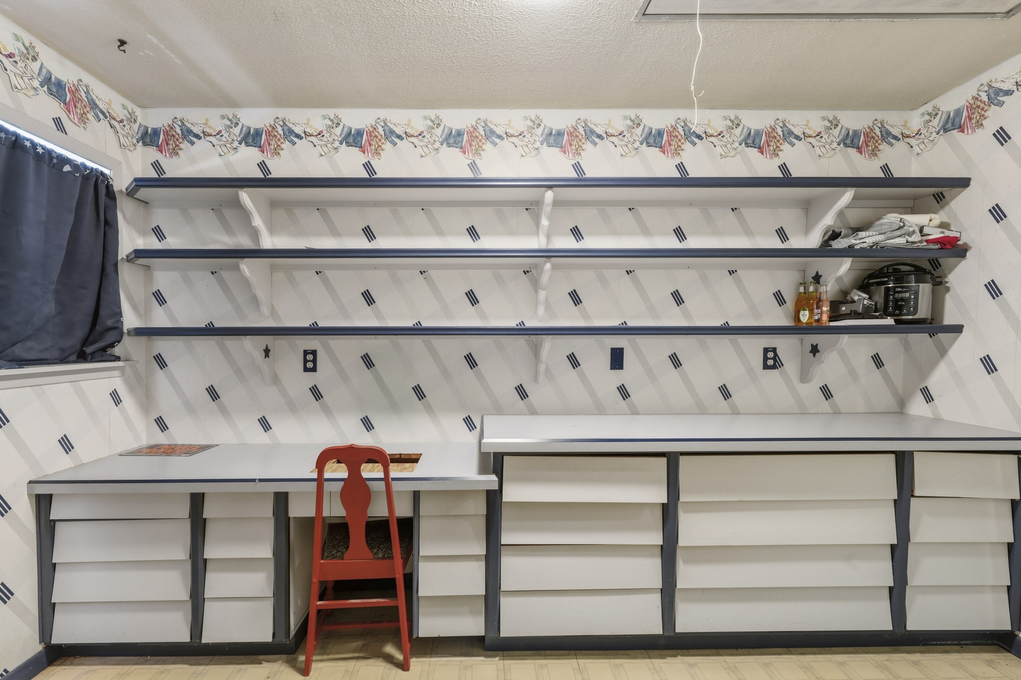 Charming workspace features ample shelving and storage with a playful wallpaper design, perfect for crafting or home projects.