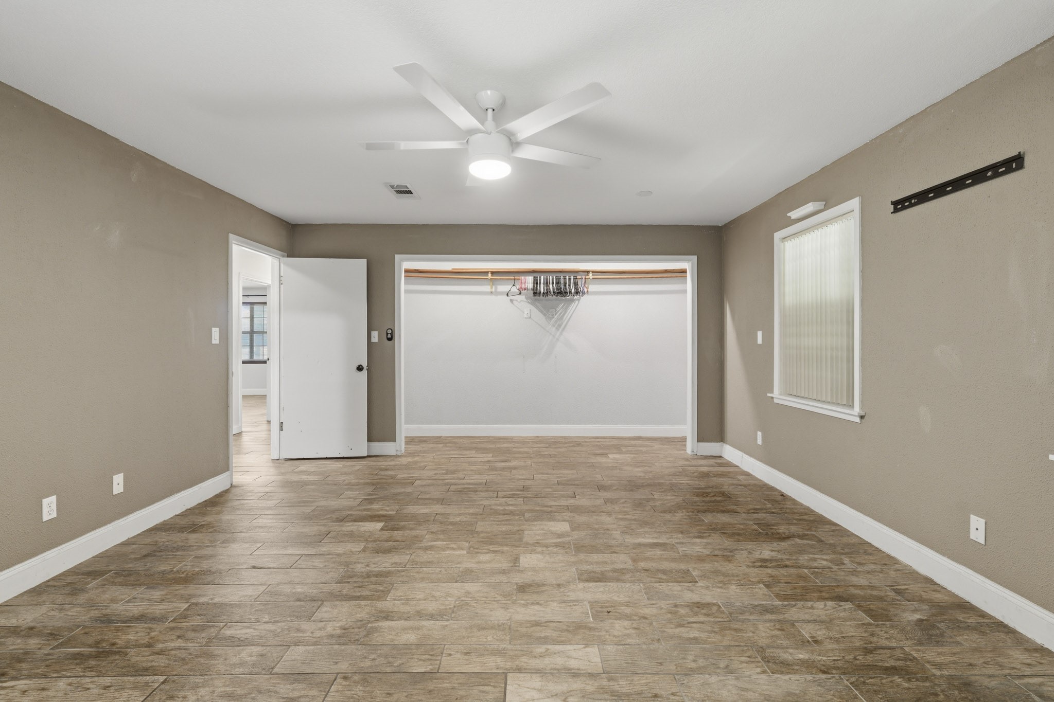 Spacious primary bedroom featuring tile flooring and a ceiling fan, with an adjacent walk-in closet for ample storage.