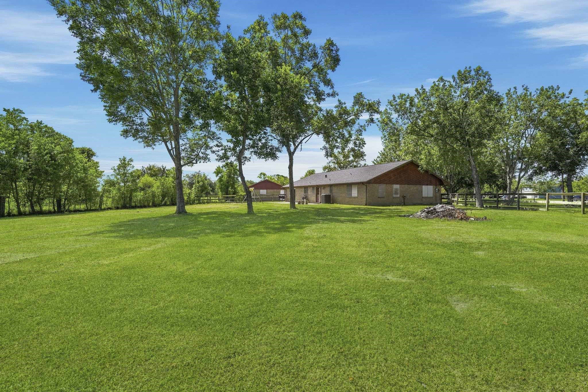 Expansive, lush backyard with mature trees and a charming single-story home, perfect for tranquil country living.