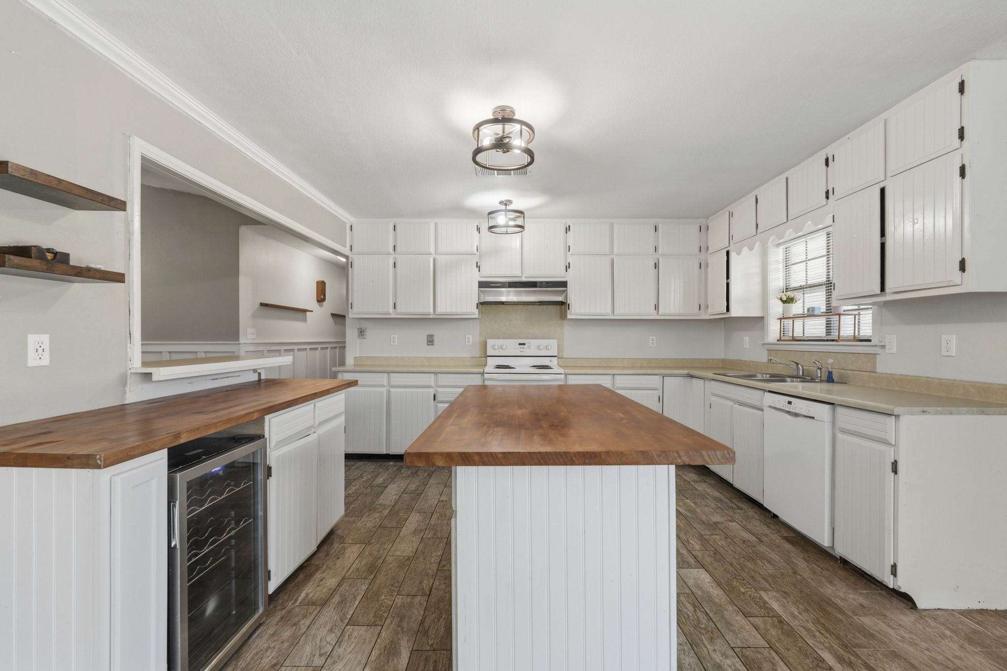 Spacious kitchen with white cabinetry and upgraded lighting, featuring a central island. Spacious kitchen with white cabinetry and upgraded lighting, featuring a central island.
