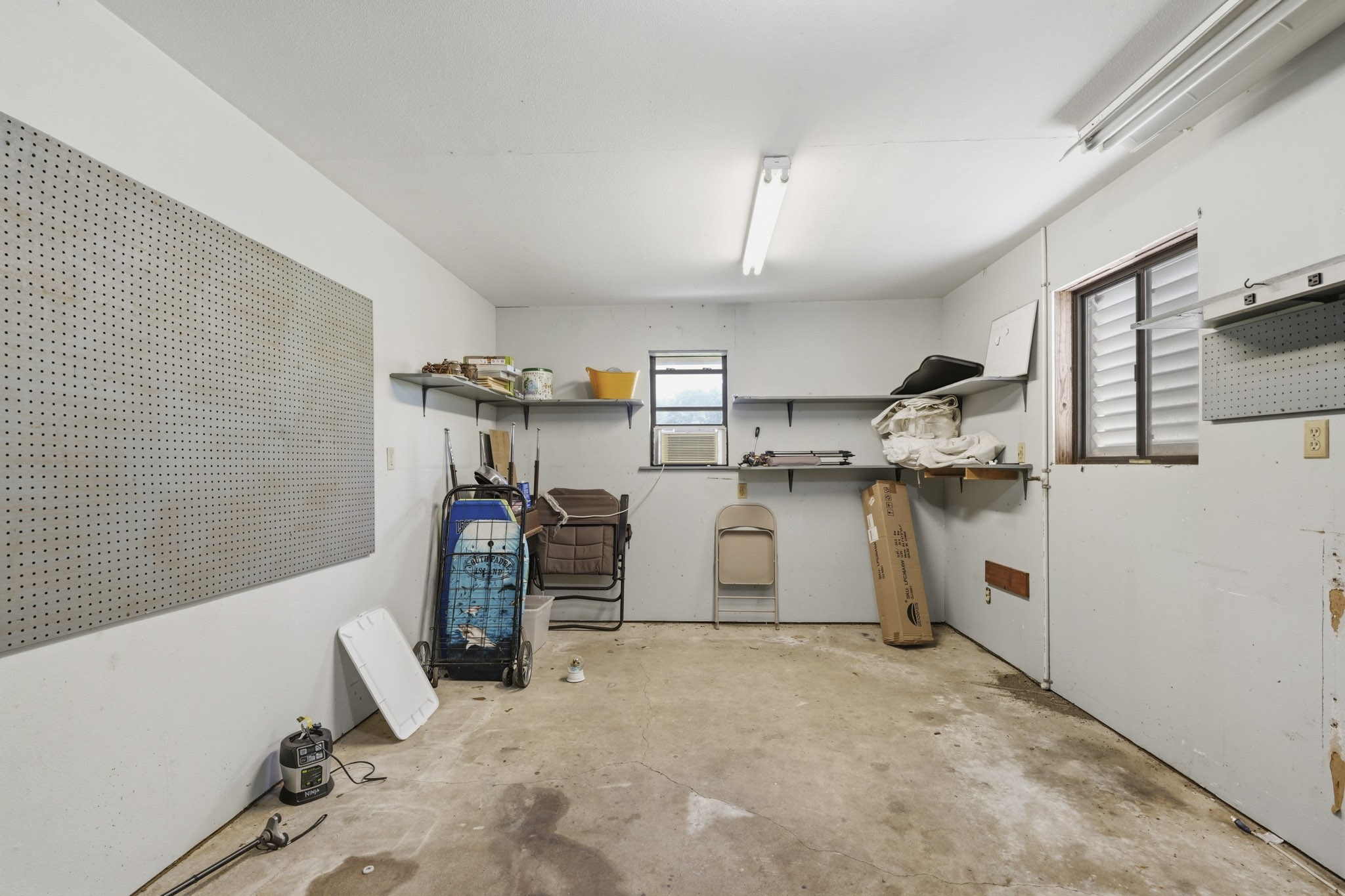 Spacious 3 car garage workshop fitted with pegboards and shelving, perfect for projects and storage.