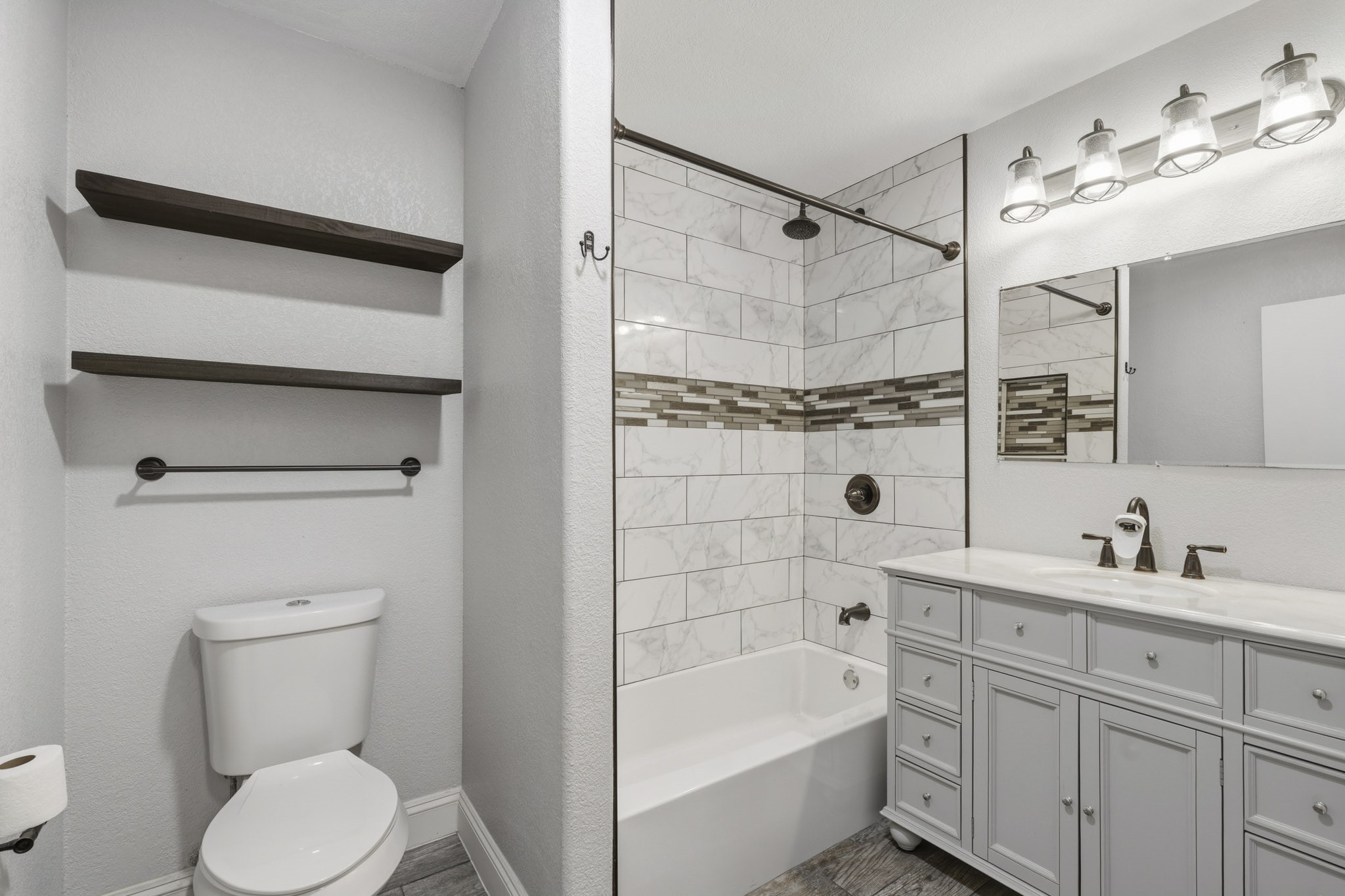 Chic and modern secondary bathroom featuring elegant tile work, a spacious vanity with sleek fixtures, complemented by open shelving for stylish storage.