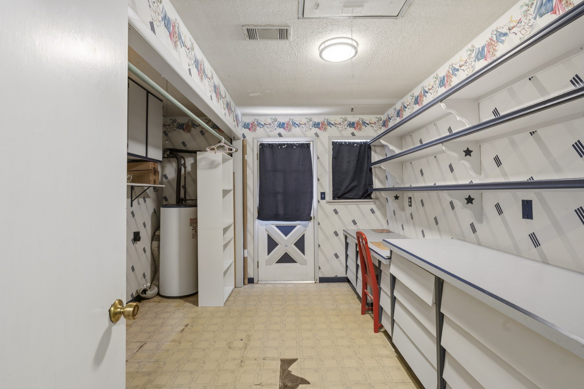 Spacious utility room with ample shelving and storage, featuring a convenient workbench area and classic cabinetry.
