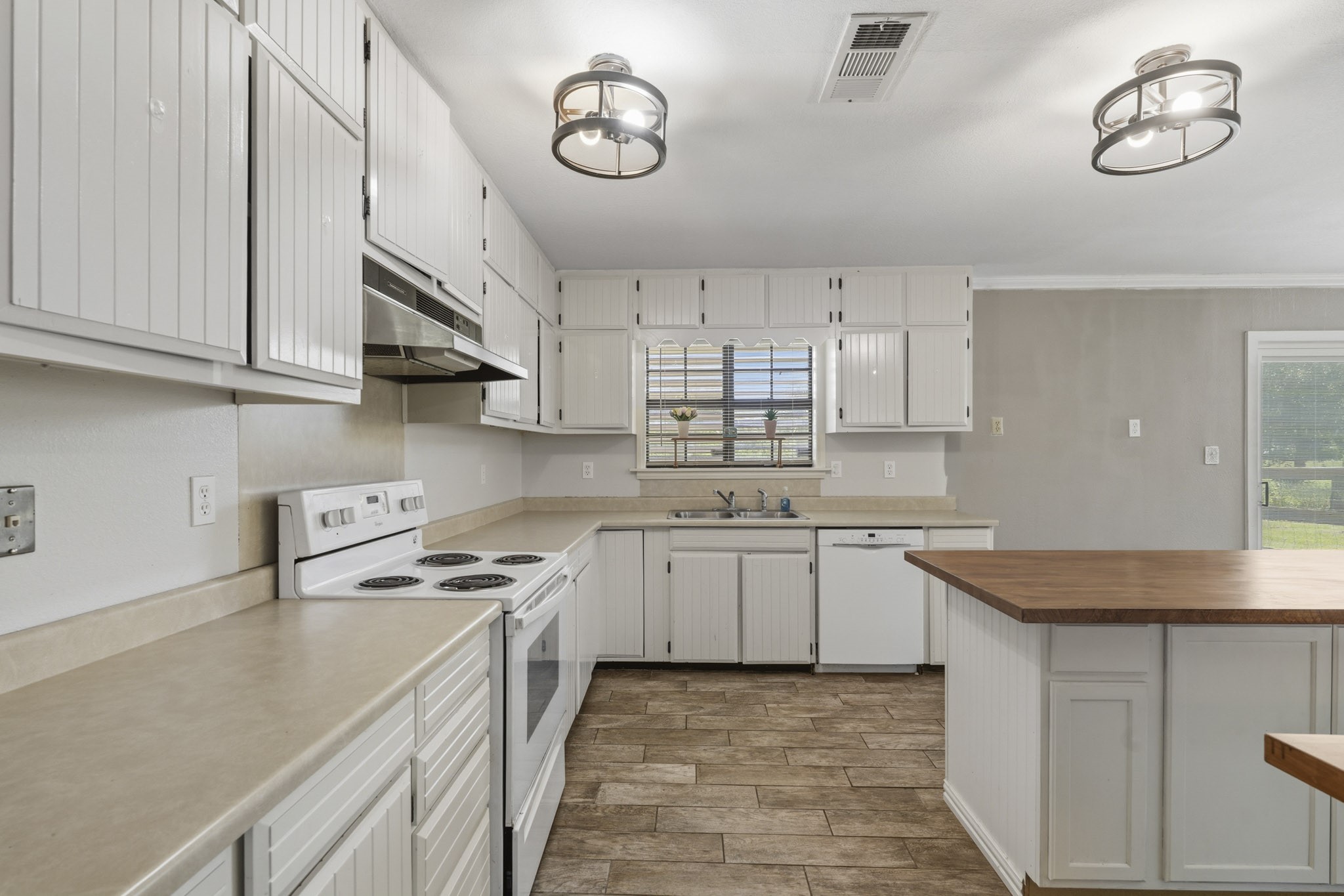 Bright and spacious kitchen with modern lighting, white cabinetry, and a central island, perfect for cooking and entertaining. Bright and spacious kitchen with modern lighting, white cabinetry, and a central island, perfect for cooking and entertaining.