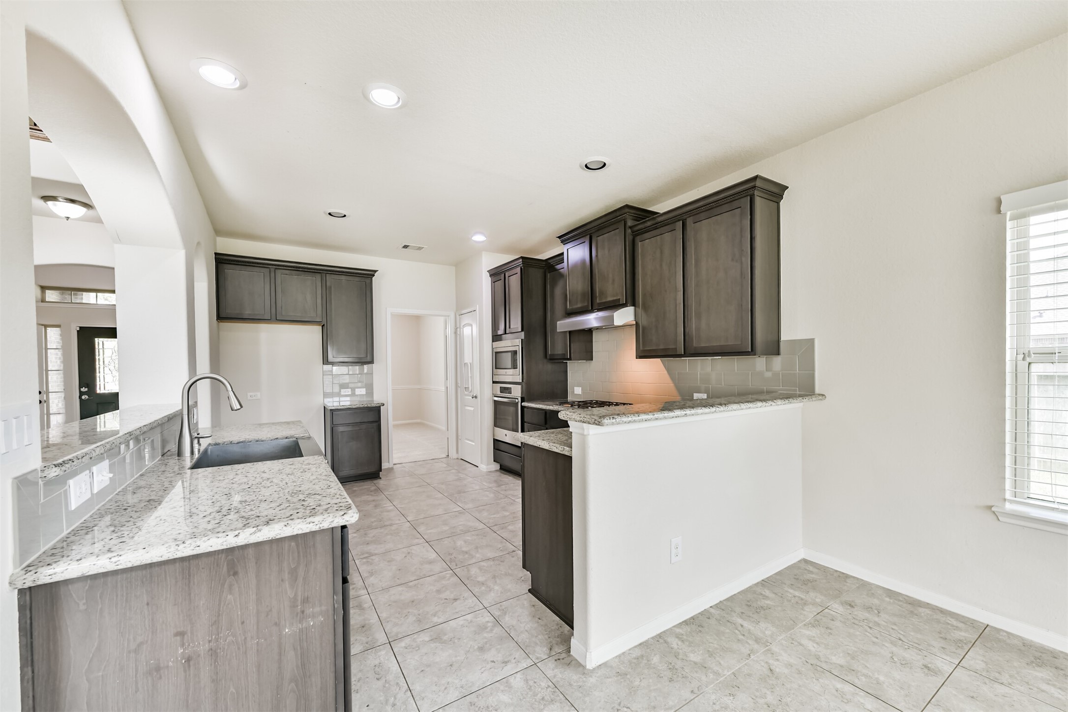 This modern kitchen features sleek granite countertops, rich cabinetry, and a convenient open layout, perfect for entertaining and daily living.