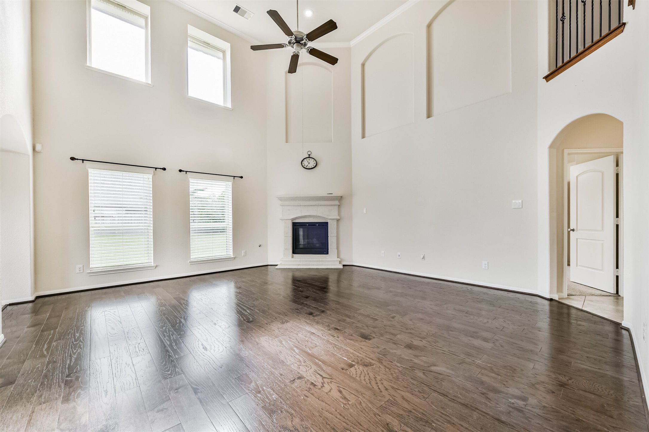 Expansive living area featuring soaring ceilings, abundant natural light, and elegant floors, complete with a cozy fireplace and stylish architectural details.