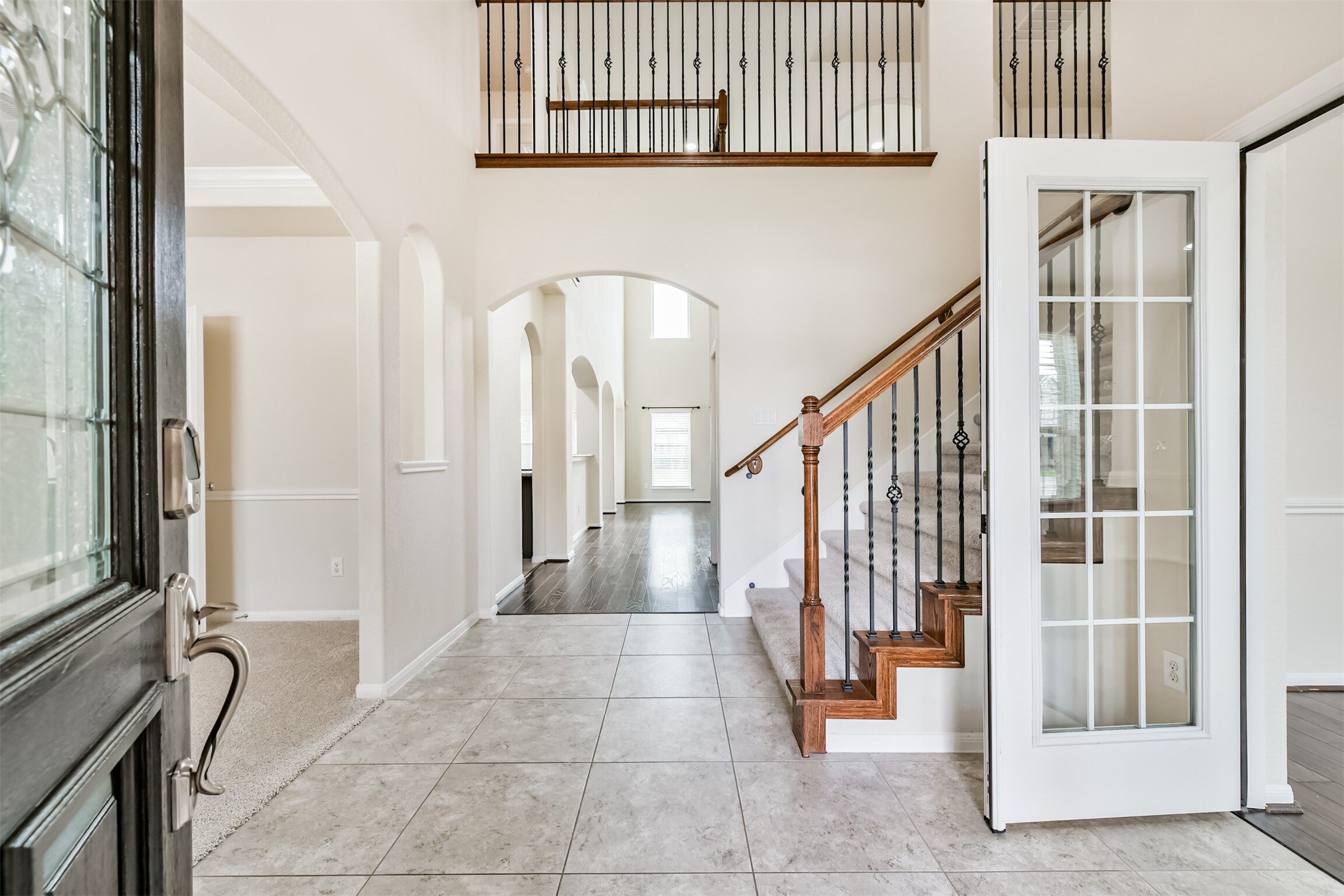 Welcome to a grand foyer featuring elegant tile flooring, a striking staircase, and abundant natural light, setting the tone for the rest of this beautiful home.