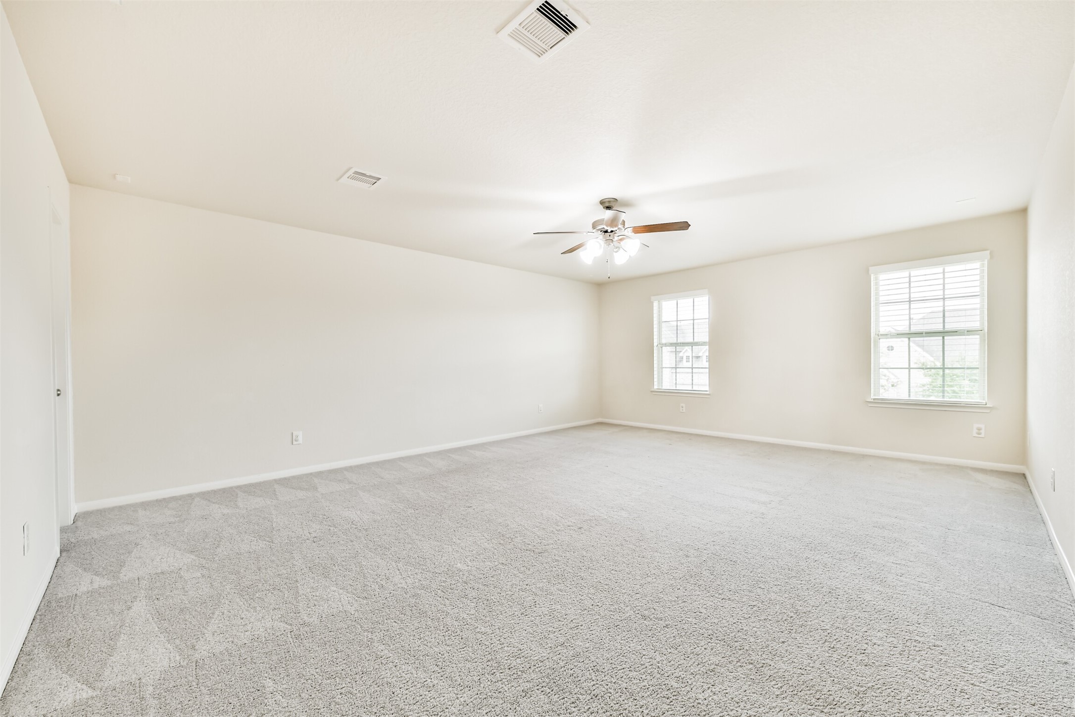 Spacious upstairs game room with abundant natural light and plush carpeting, perfect for entertainment and relaxation.