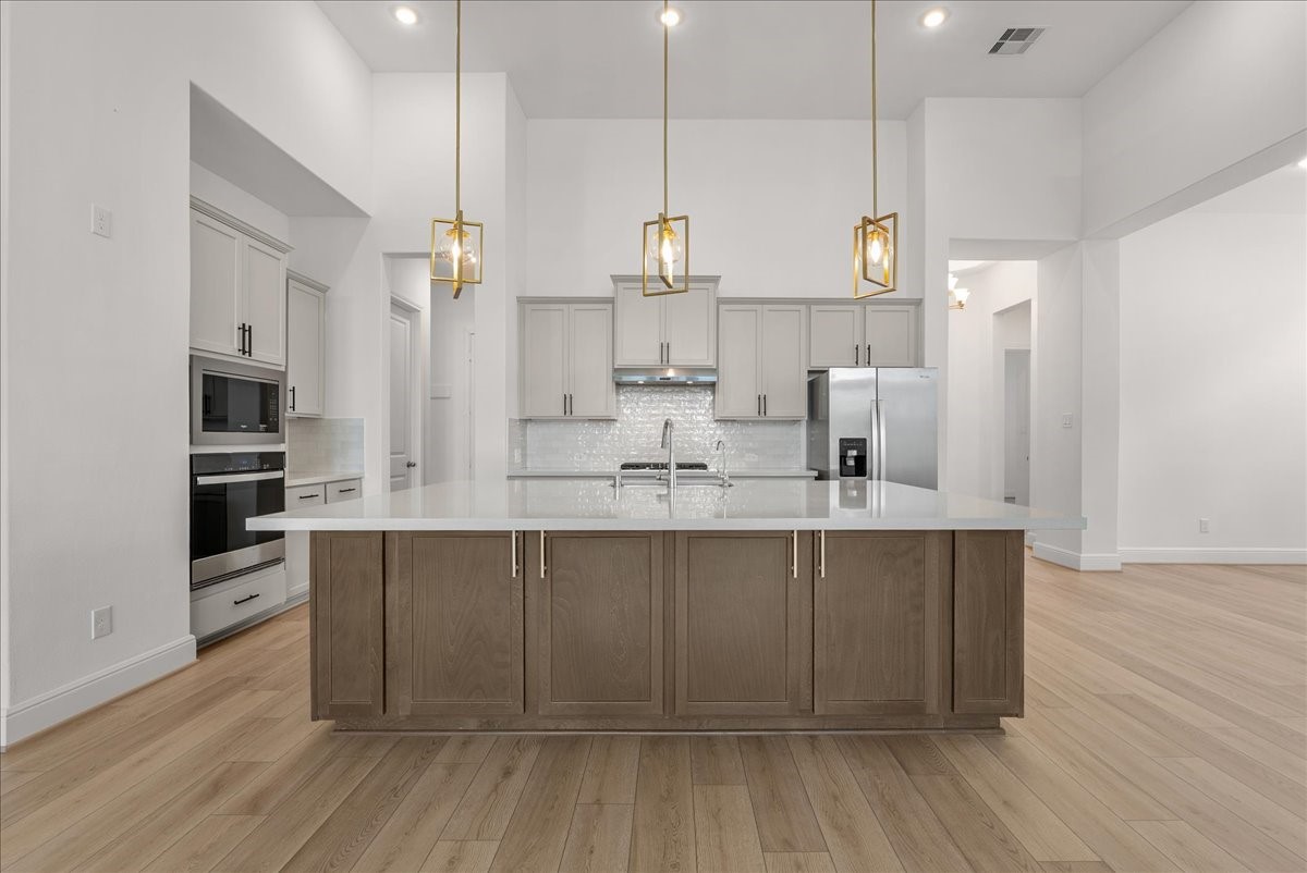 The beautifully appointed kitchen opens seamlessly to the living room and features an oversized island, stainless steel appliances, and 42-inch cabinetry with crown molding.