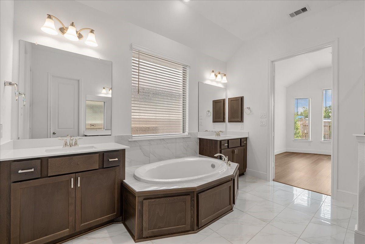 he secluded primary retreat boasts a spa-inspired en-suite bath with dual vanities, soaking tub, walk-in shower, and generous walk-in closet.
