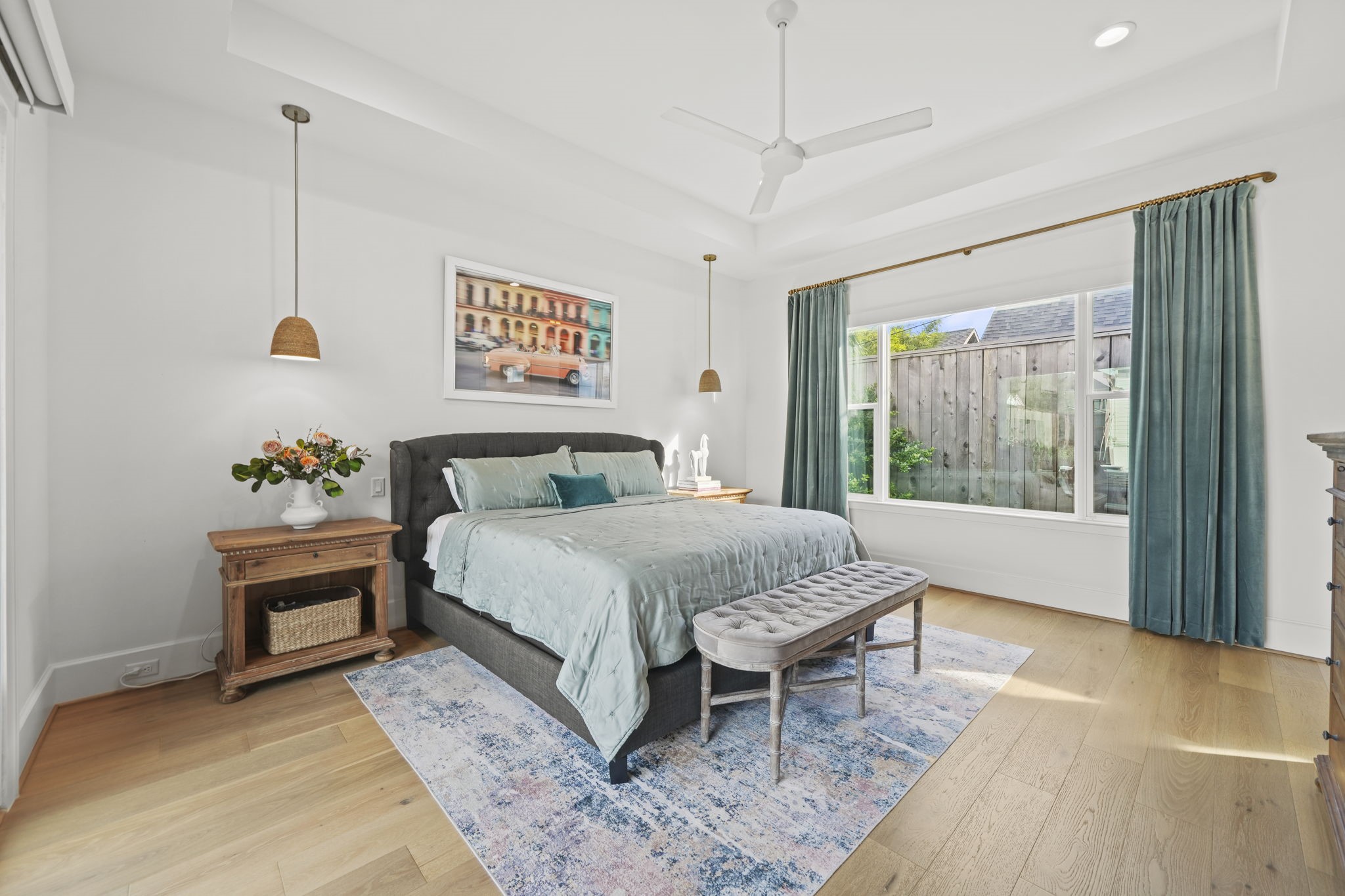 The primary bedroom has the same gorgeous wood flooring that is throughout the rest of the home and custom pendant lighting!
