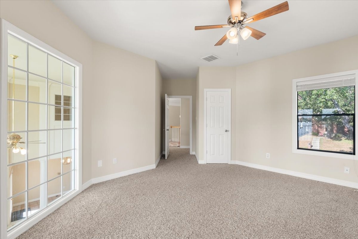 Upstairs bedroom with french doors leading to covered deck. Take in the views from the top floor. Walk in closet with built ins and ceiling fan