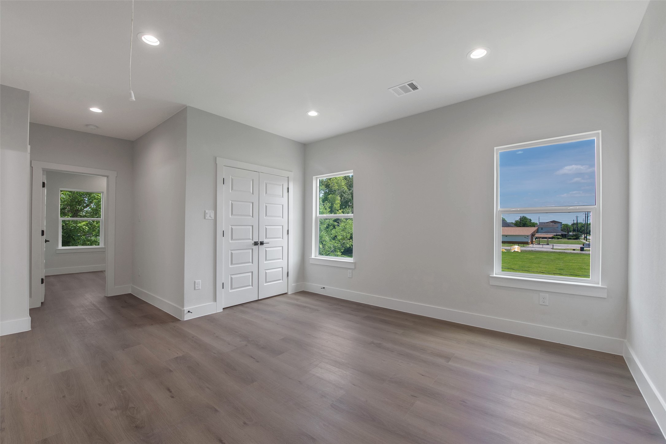A spacious upstairs flex space, filled with natural light from the windows, offers versatile use for work, play, or relaxation, with bedrooms located just off the space for added convenience and privacy, along with a utility closet for practical storage.