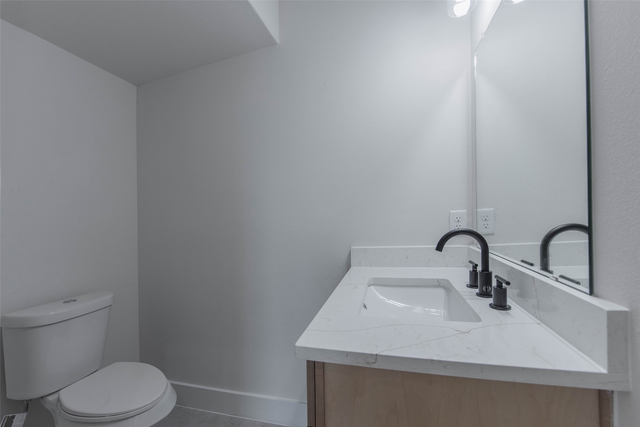 The powder room is conveniently located just off the living room and features quartz countertops and a stylish vanity, offering a bright and functional space.