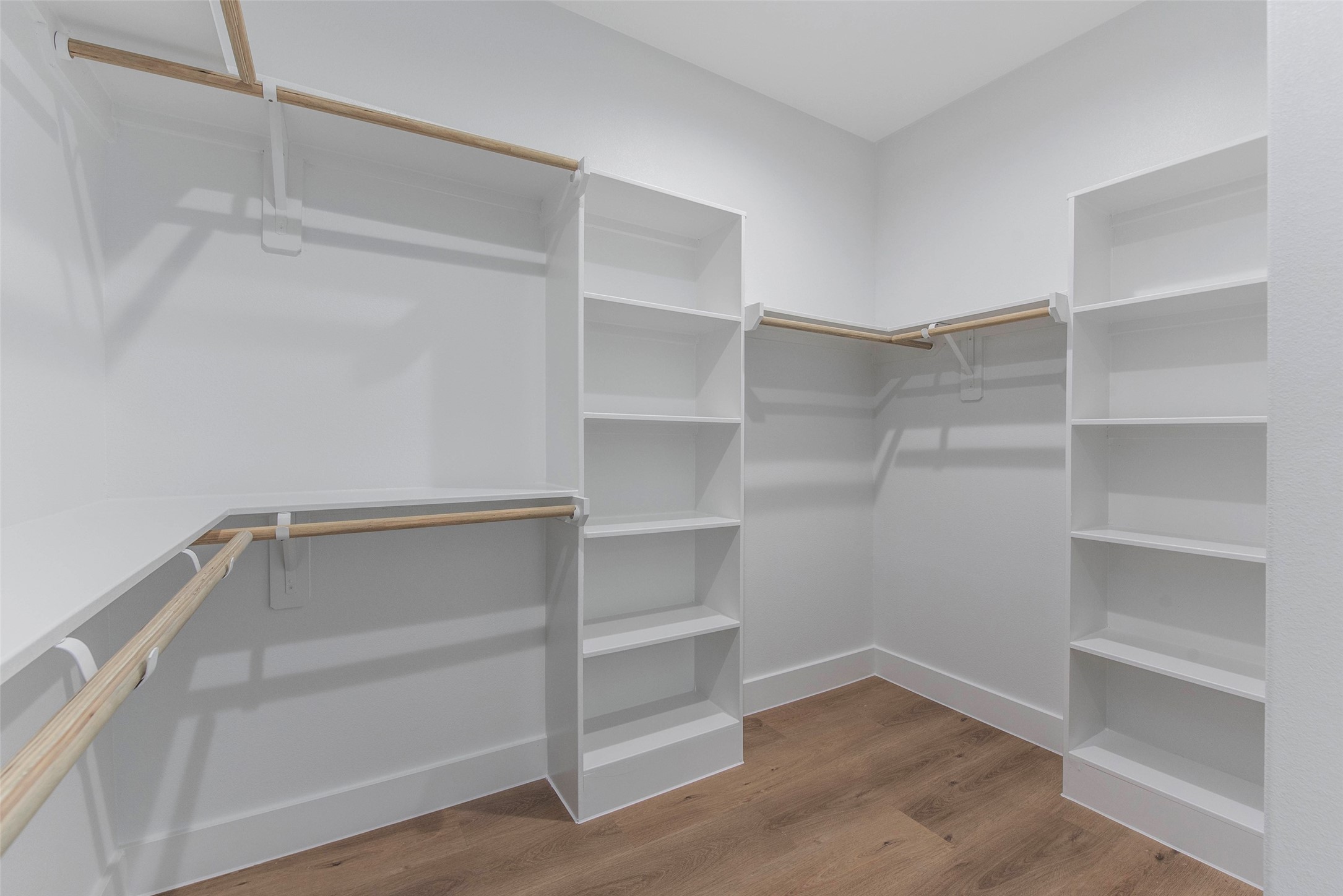 An ample walk-in closet featuring built-in shelving and generous hanging space, thoughtfully designed for organized, effortless storage.
