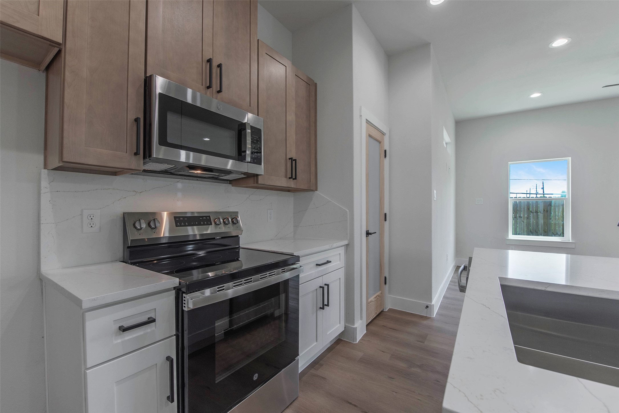 The kitchen is fully equipped with quartz countertops, a cooking range, microwave, and dishwasher, combining style and functionality for everyday living. The kitchen is fully equipped with quartz countertops, a cooking range, microwave, and dishwasher, combining style and functionality for everyday living.