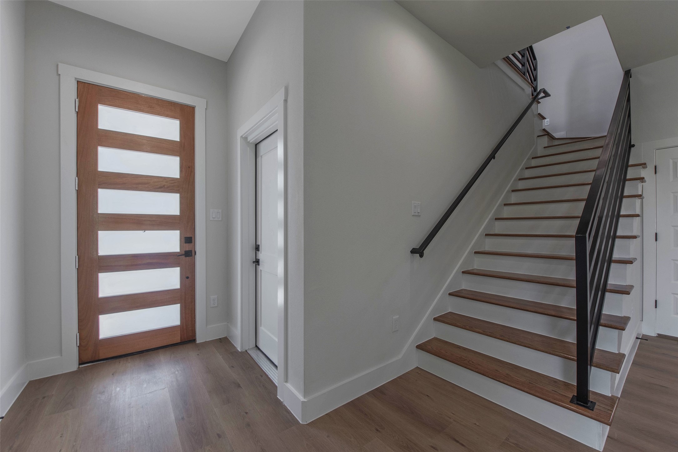 The door to the right leads to a spacious garage with ample room for parking and storage. Glass inserts in the modern front door invite natural light.