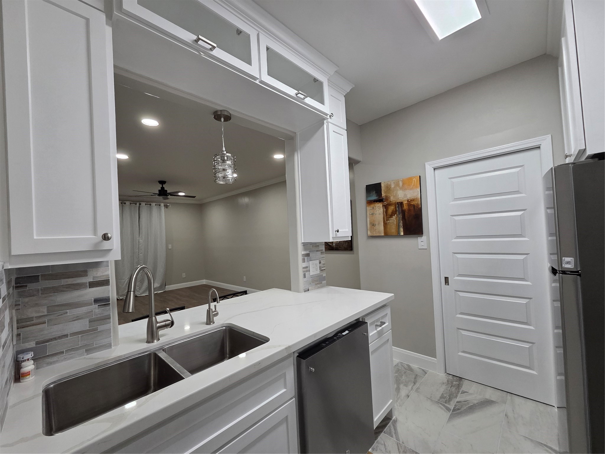 A closer view of what the kitchen offers - hot water dispensers (for instant coffee, soups & more), Pendant light, LED kitchen light, Tile floors, backsplash and a pocket door to pantry and laundry room. A nice view to dining and living area.